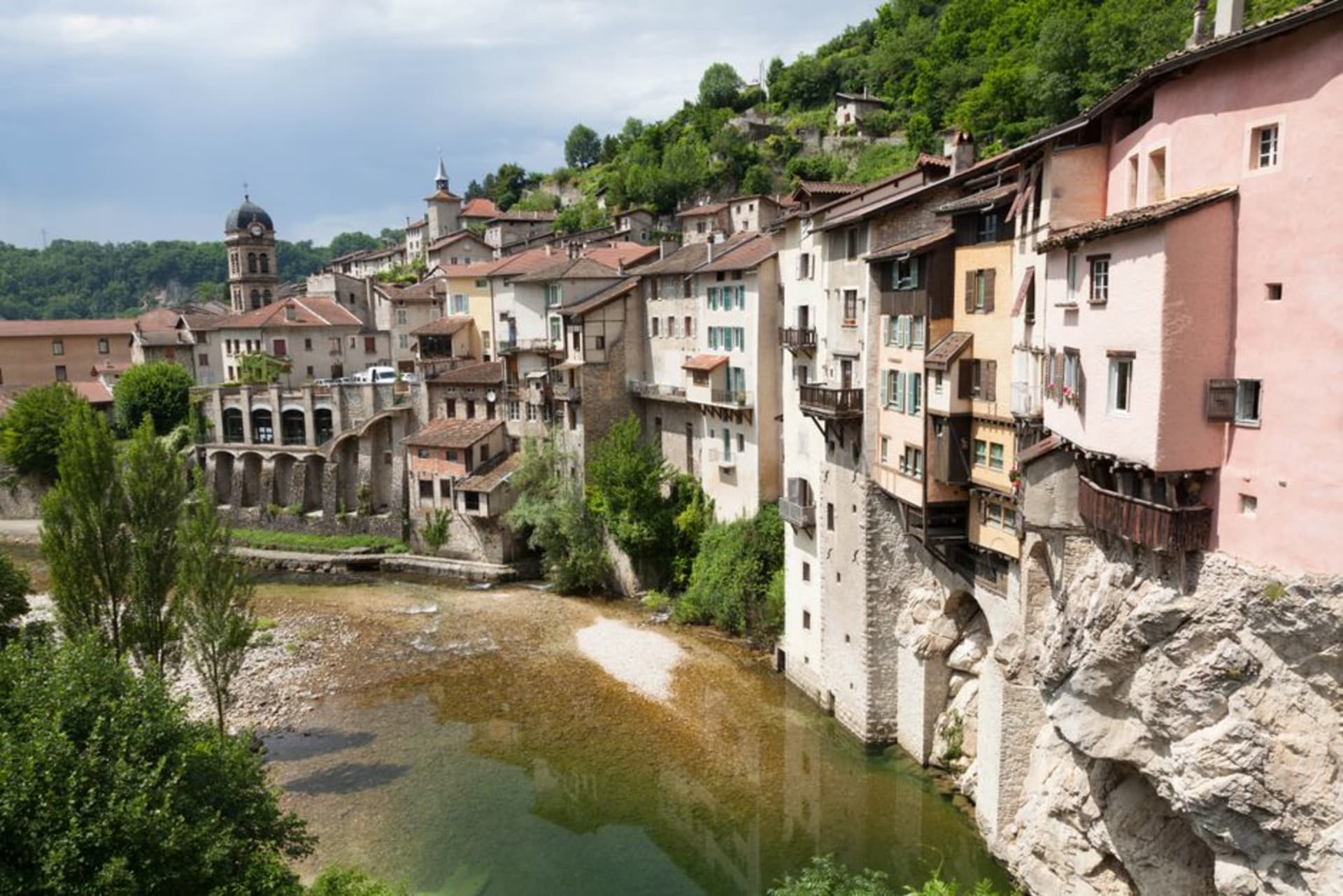 The pink granite ramparts and round towers of Semur-en-Auxois rising above a bend of the Armançon river