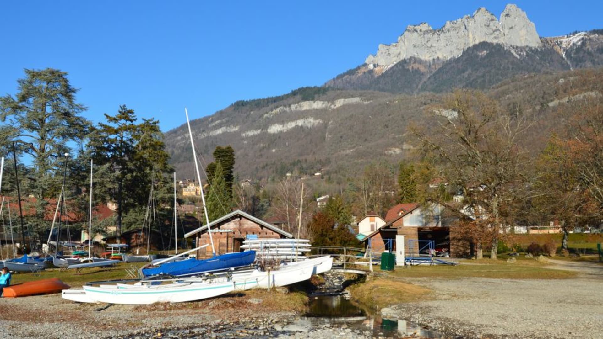 The lakeside village of Talloires on Lac d'Annecy with the old priory buildings and wooded hills reflected in still turquoise water