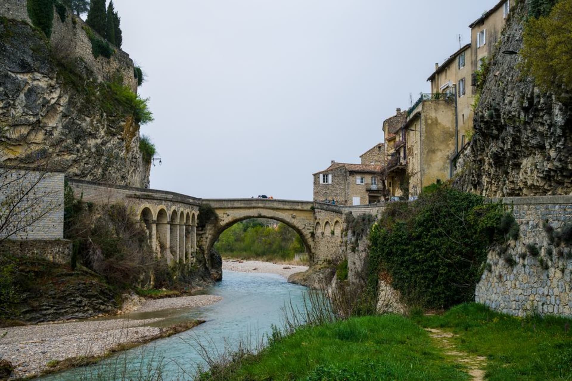 The ancient Roman bridge over the Ouvèze river at Vaison-la-Romaine with the medieval hilltop town visible behind