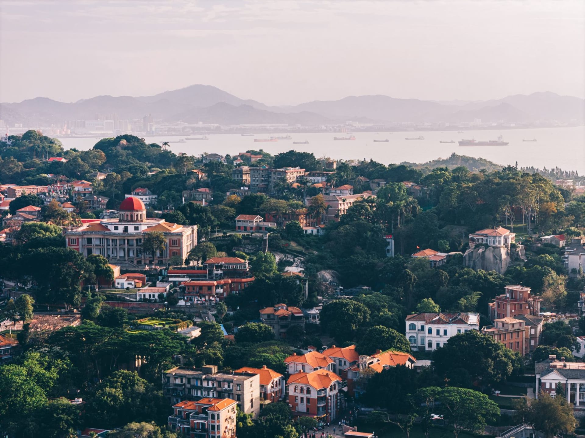 Aerial view of Gulangyu Island with colonial-era rooftops and turquoise sea surrounding Xiamen, Fujian