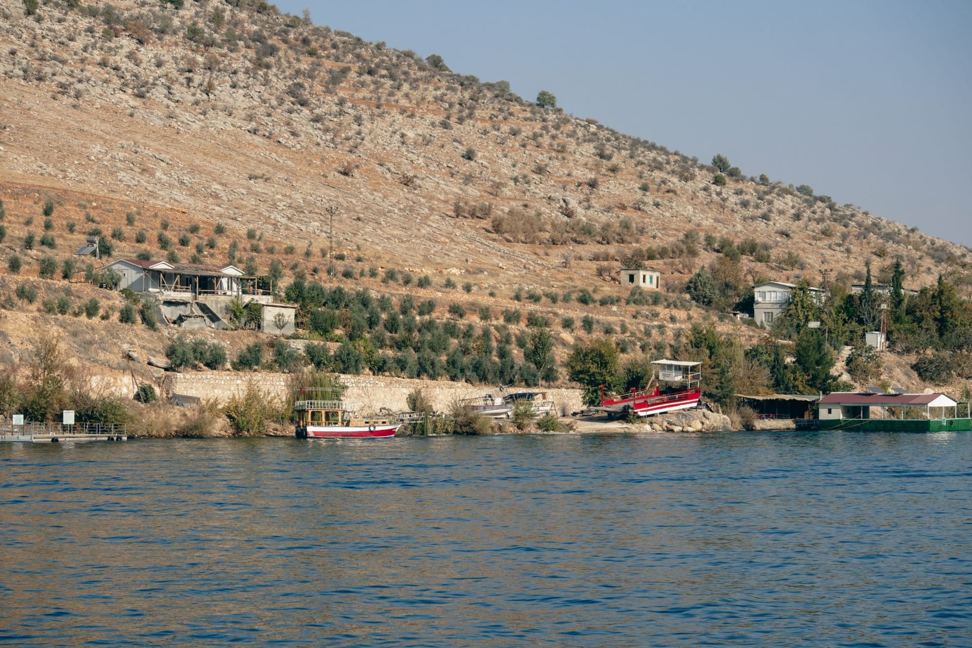 Tiberias harbor at golden hour with fishing boats reflected in the copper-lit Sea of Galilee