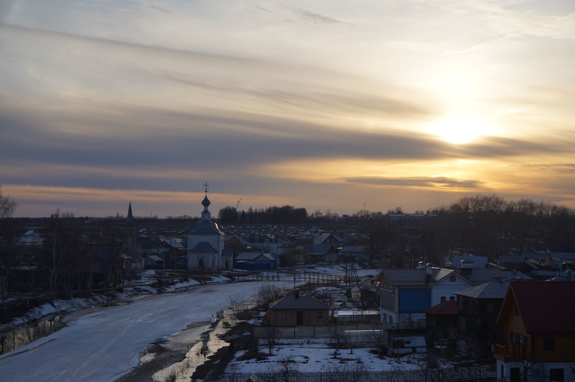Winter sunset over Suzdal's historic skyline with snow-dusted church domes glowing in golden light