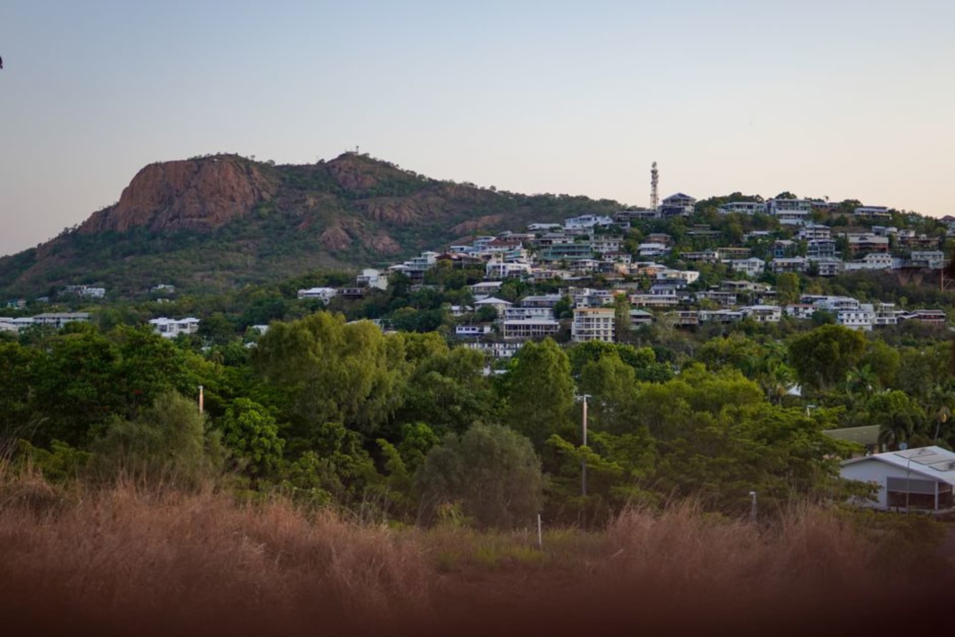 Townsville's waterfront promenade with Castle Hill rising red and rocky behind the city skyline