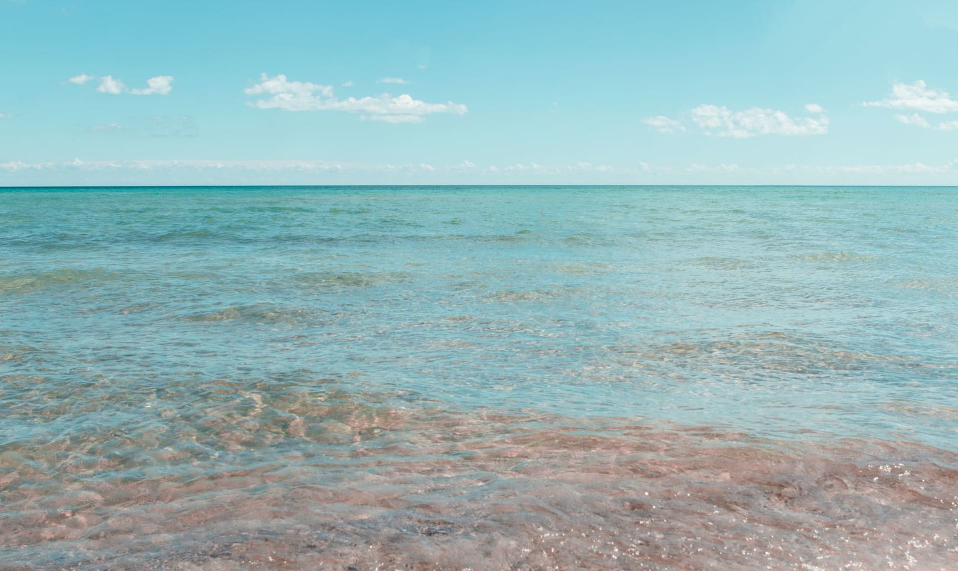 La langue de sable incurvée de Presque Isle s'étirant dans le lac Érié au coucher du soleil, le lagon protégé brillant d'ambre d'un côté et le lac ouvert bleu foncé de l'autre