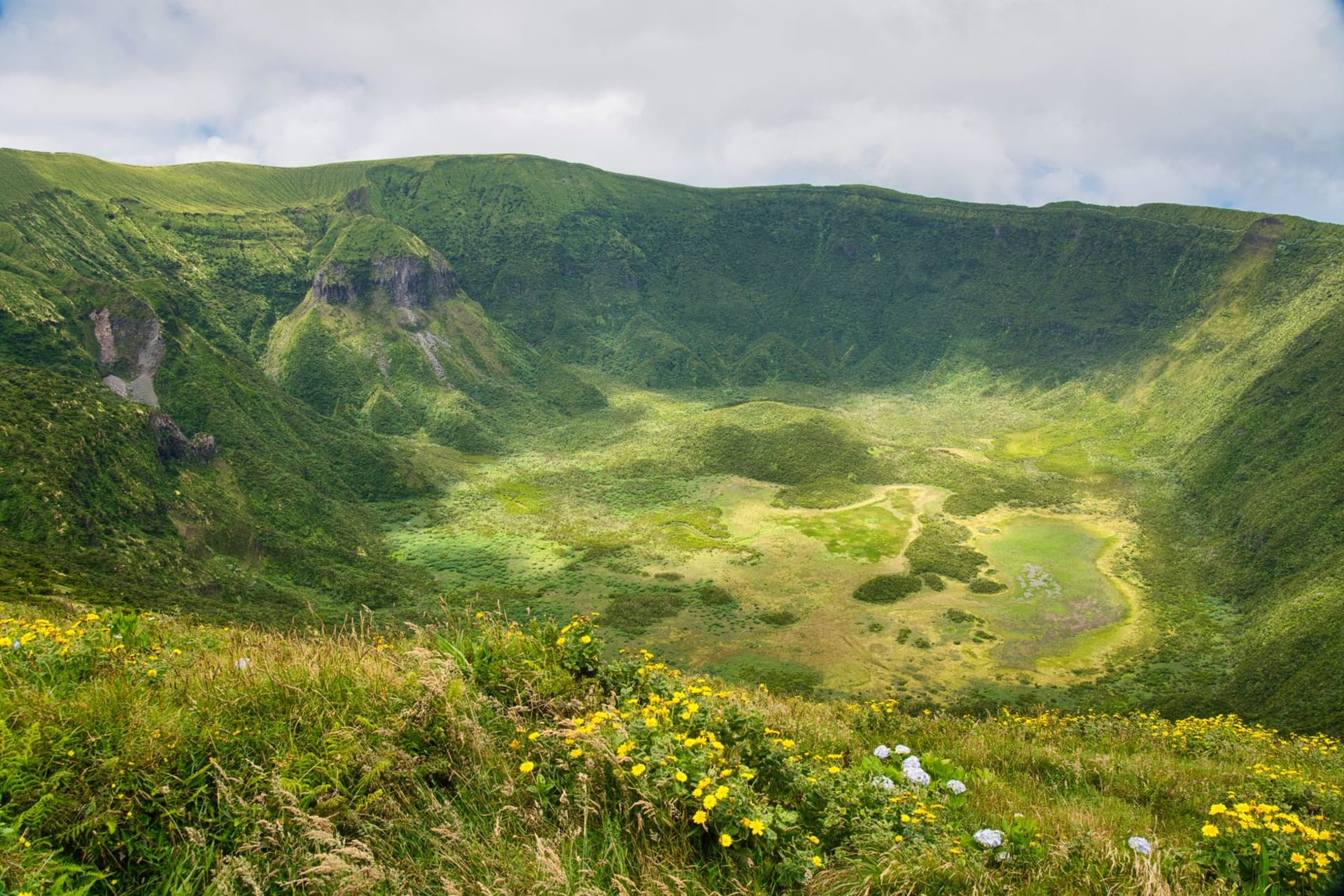 The vast green interior of Menengai Crater seen from the rim, with steam vents visible and the town of Nakuru below on the Rift Valley floor