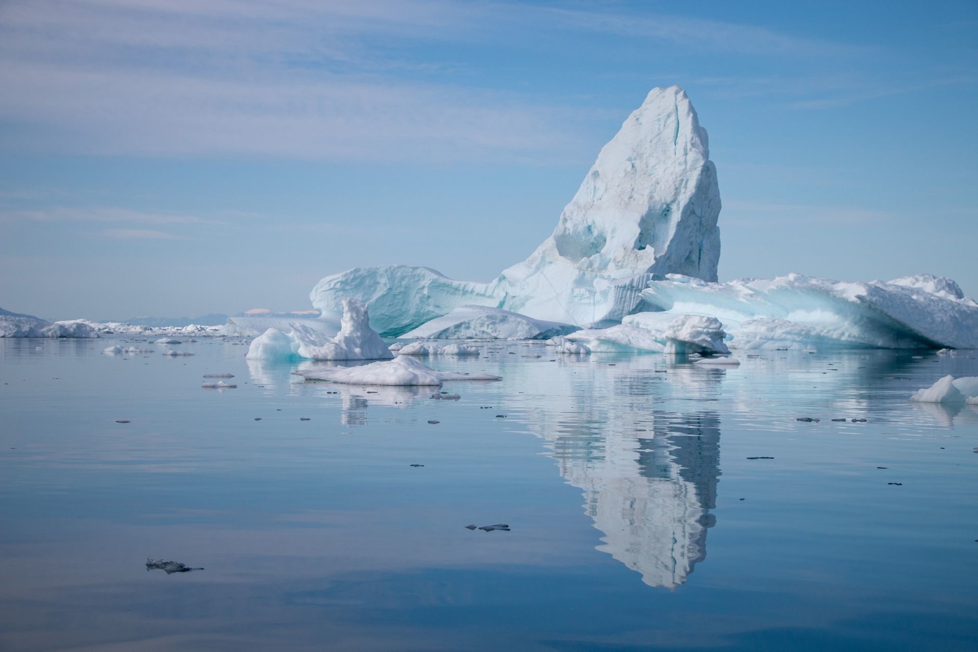 Black basalt cliffs of Disko Island plunging to iceberg-filled Disko Bay with the vast white ice sheet visible on the distant horizon