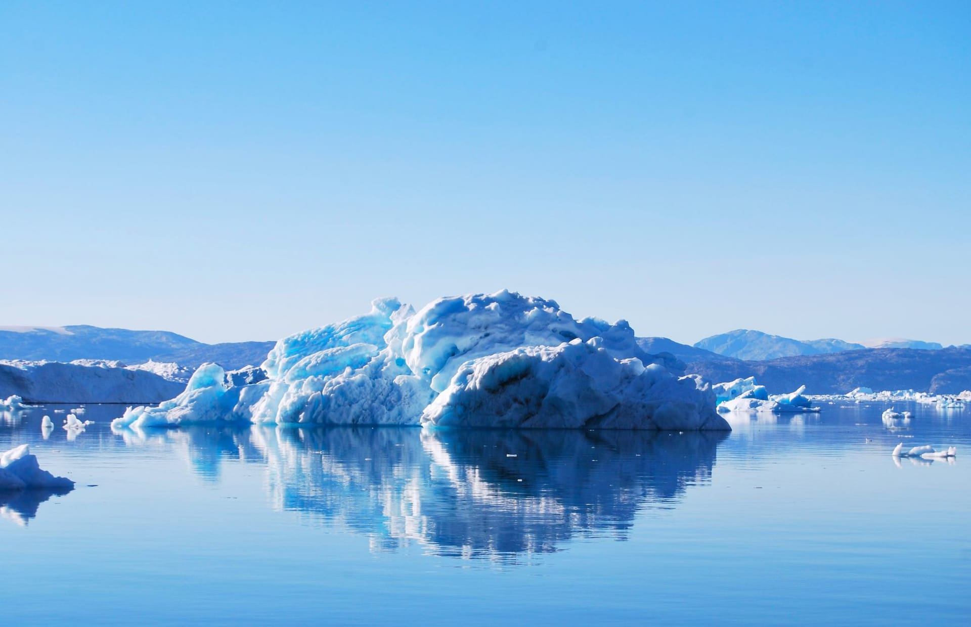 Massive iceberg reflected perfectly in the glassy stillness of Tiniteqilaaq fjord, East Greenland