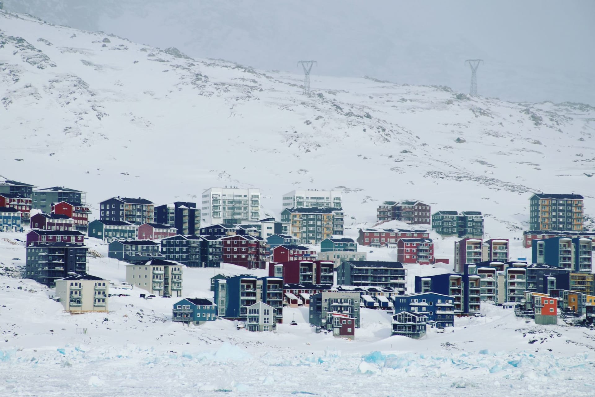 Kangerlussuaq fjord reflecting the surrounding brown tundra hills under a vast Arctic sky, with musk oxen silhouetted on the ridge above