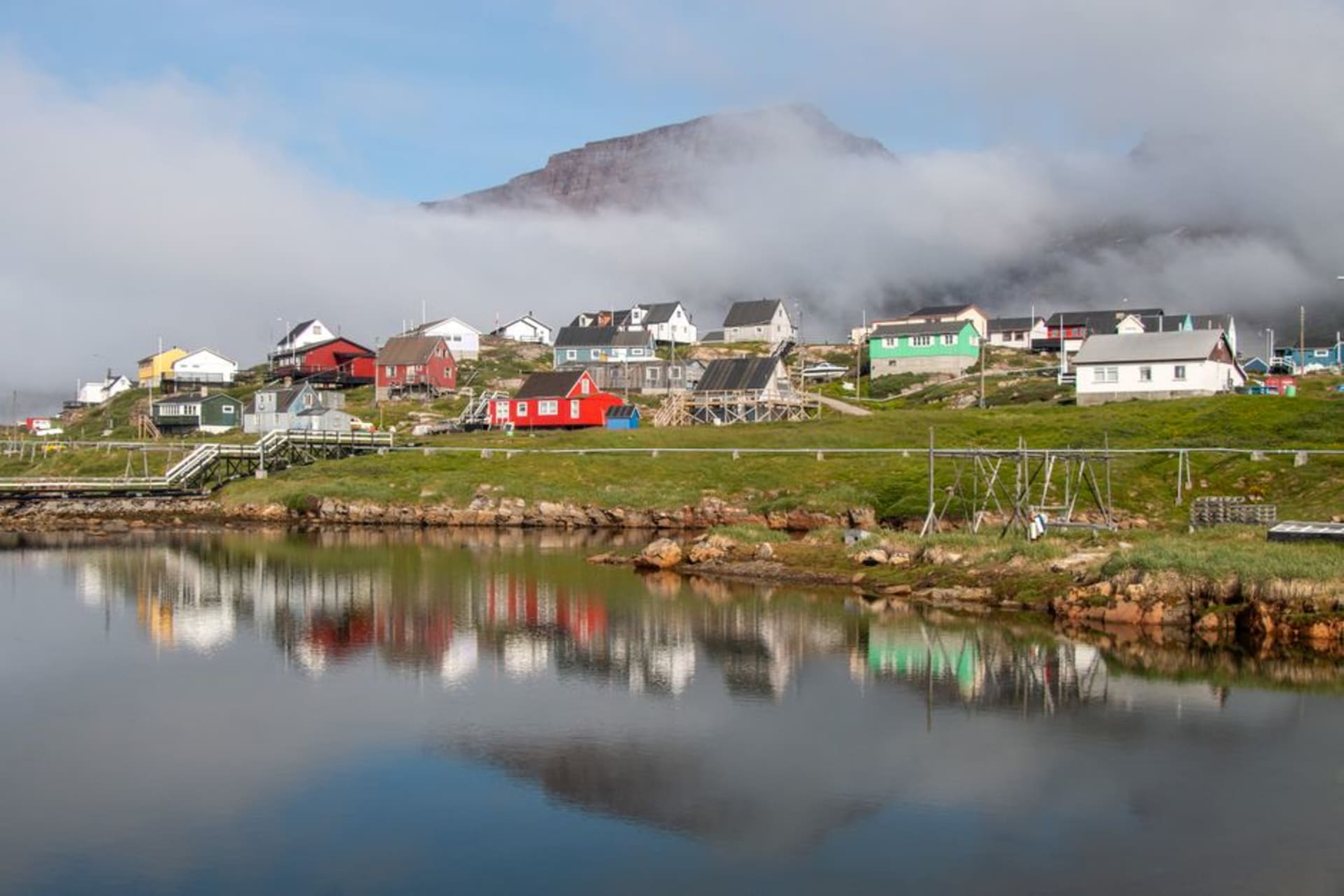 Casas de madera de colores de Qeqertarsuaq bordeando el puerto con icebergs a la deriva en la bahía de Disko