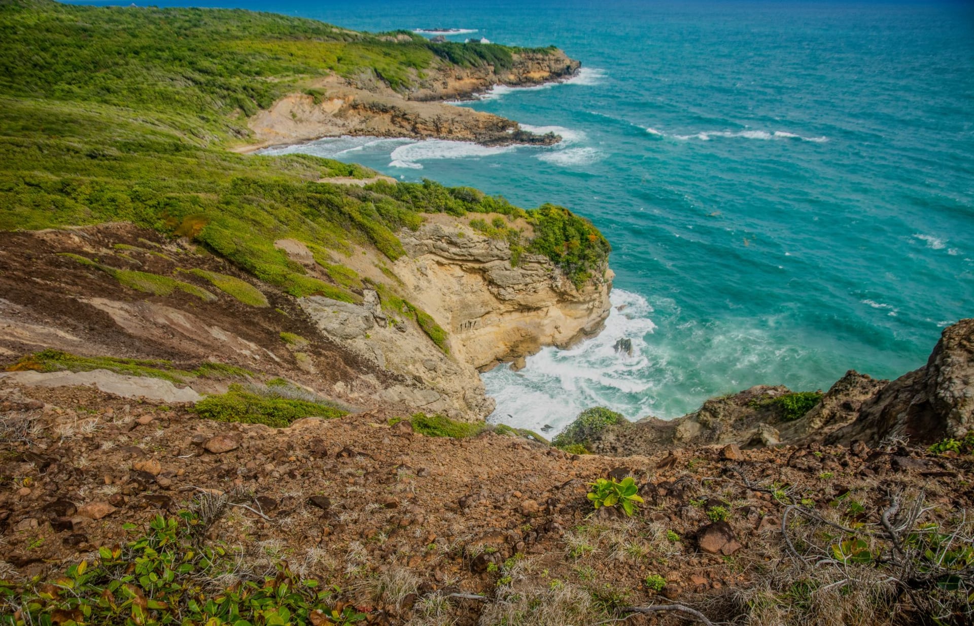 Dramatic eroded limestone rock formations at Pointe des Châteaux with crashing Atlantic waves on one side and calm turquoise Caribbean water on the other