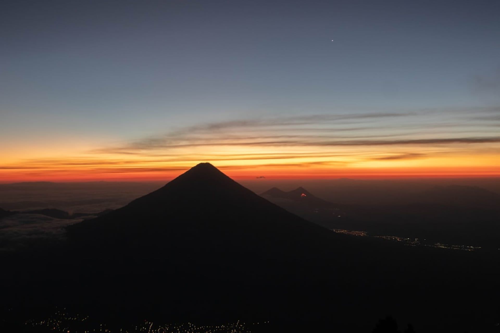Des randonneurs observant le Volcán de Fuego entrer en éruption de nuit depuis le camp de l'Acatenango