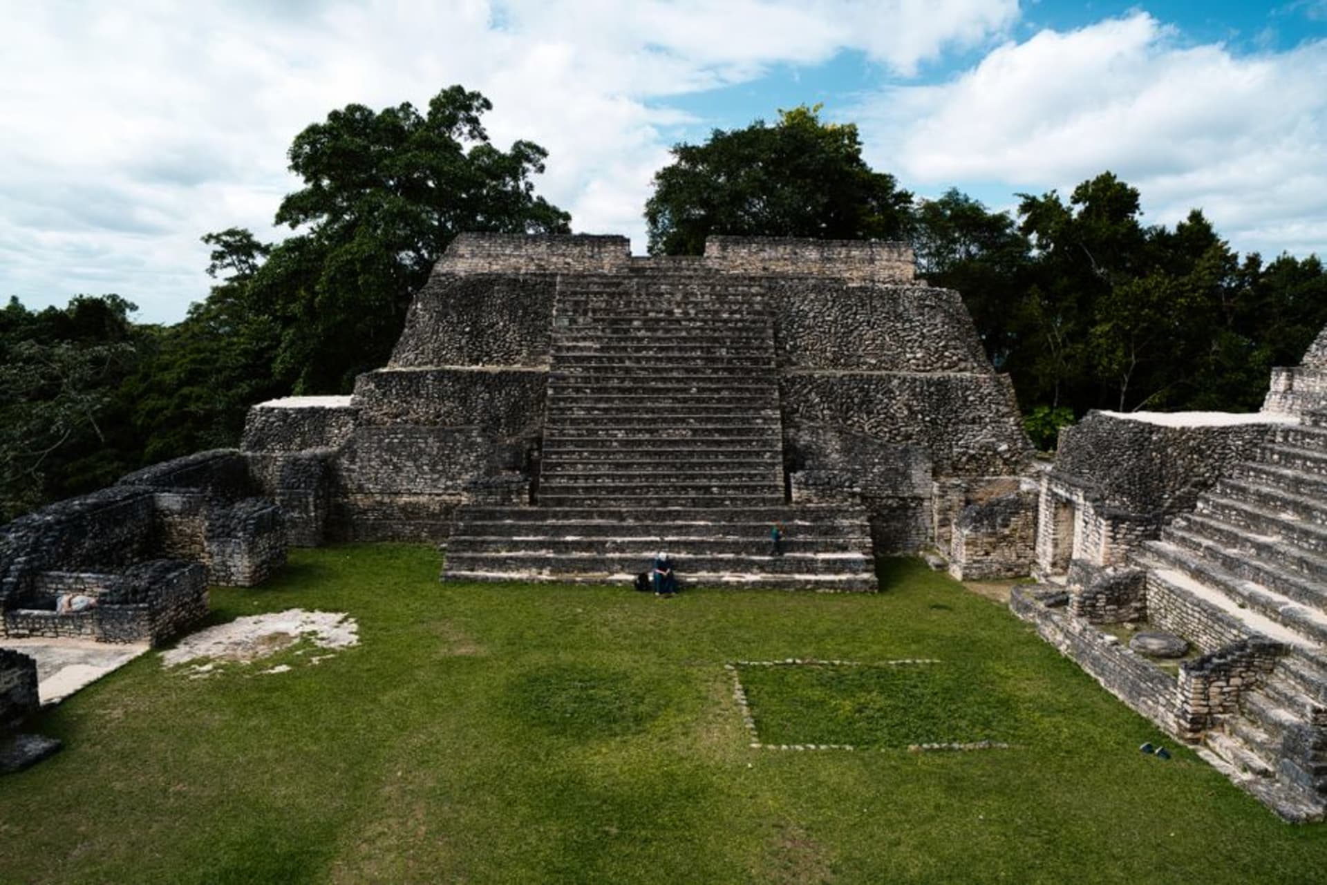 The stepped stucco pyramids of Zaculeu archaeological site under a pale highland sky, surrounded by pine forest