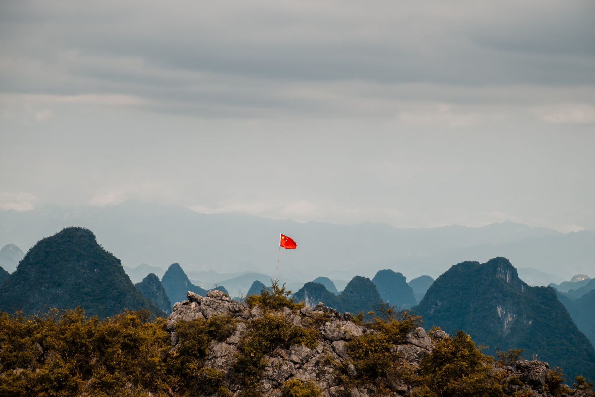 The circular arch of Moon Hill limestone peak near Yangshuo seen from below, framing a circle of blue sky against grey-white karst rock