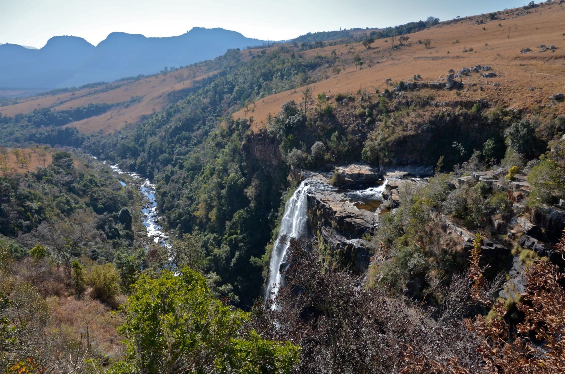 Aerial view of a waterfall cascading through dense tropical forest in the highlands of West Africa