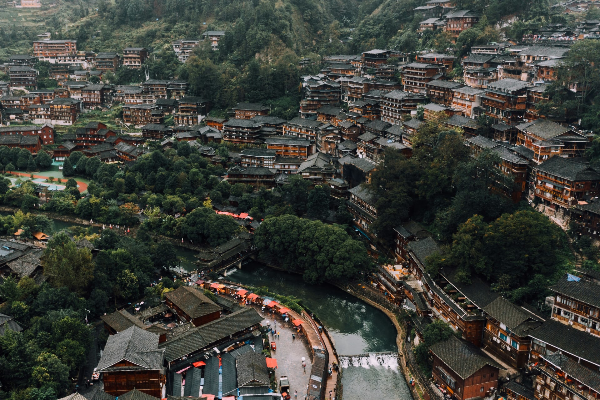 Aerial view of a traditional minority village nestled in the forested mountains of Guizhou, China
