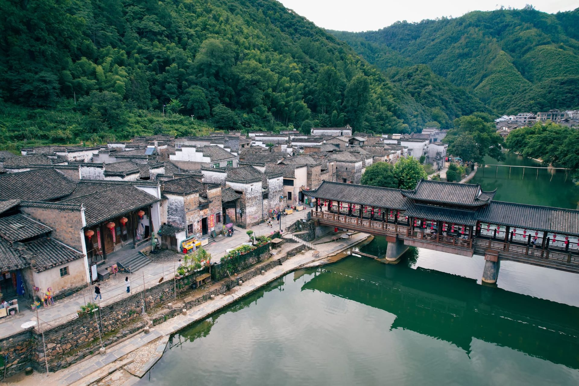 Five pagoda-style Dong drum towers rising above the wooden rooftops of Zhaoxing village, surrounded by terraced rice fields