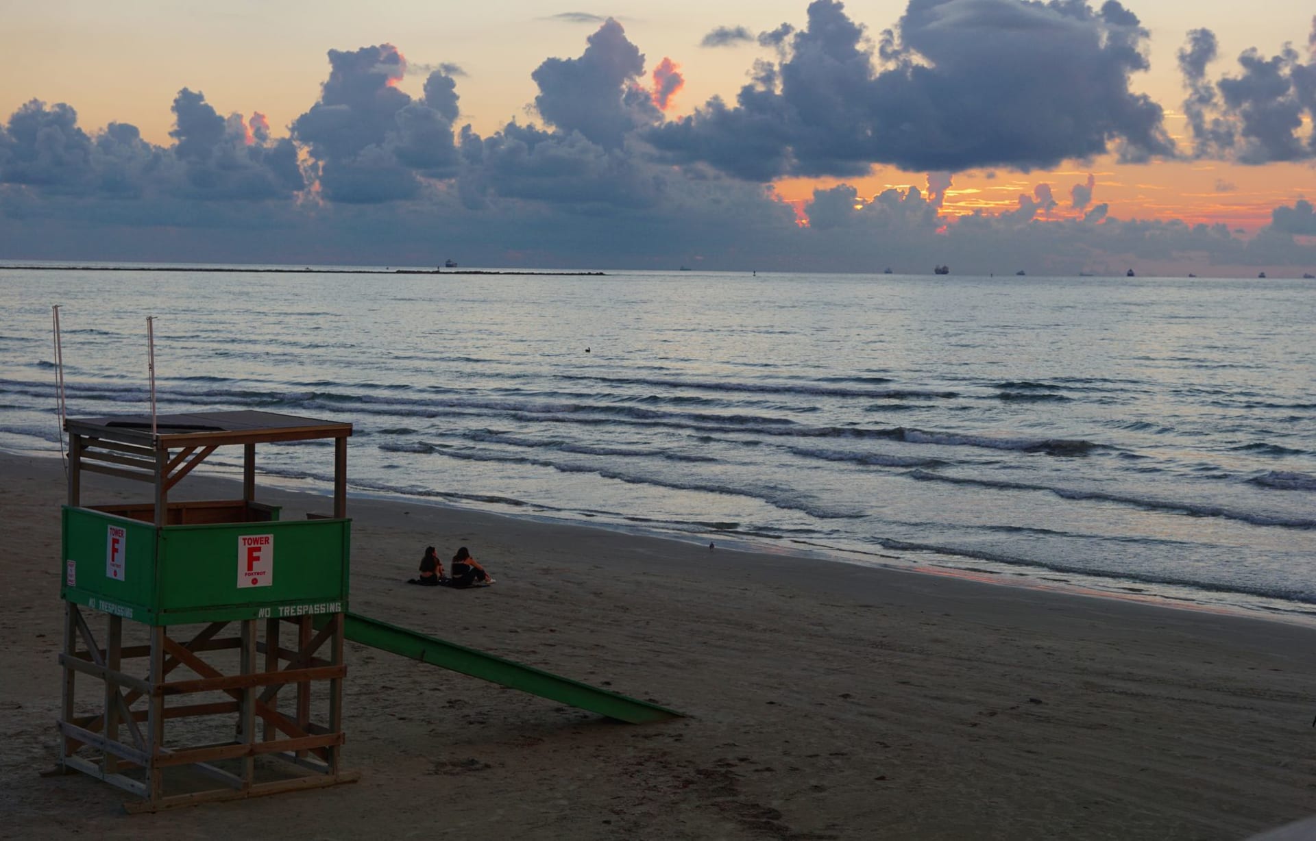 Port Aransas fishing pier at sunrise, pelicans perched on pilings, pastel sky reflected in calm Gulf waters