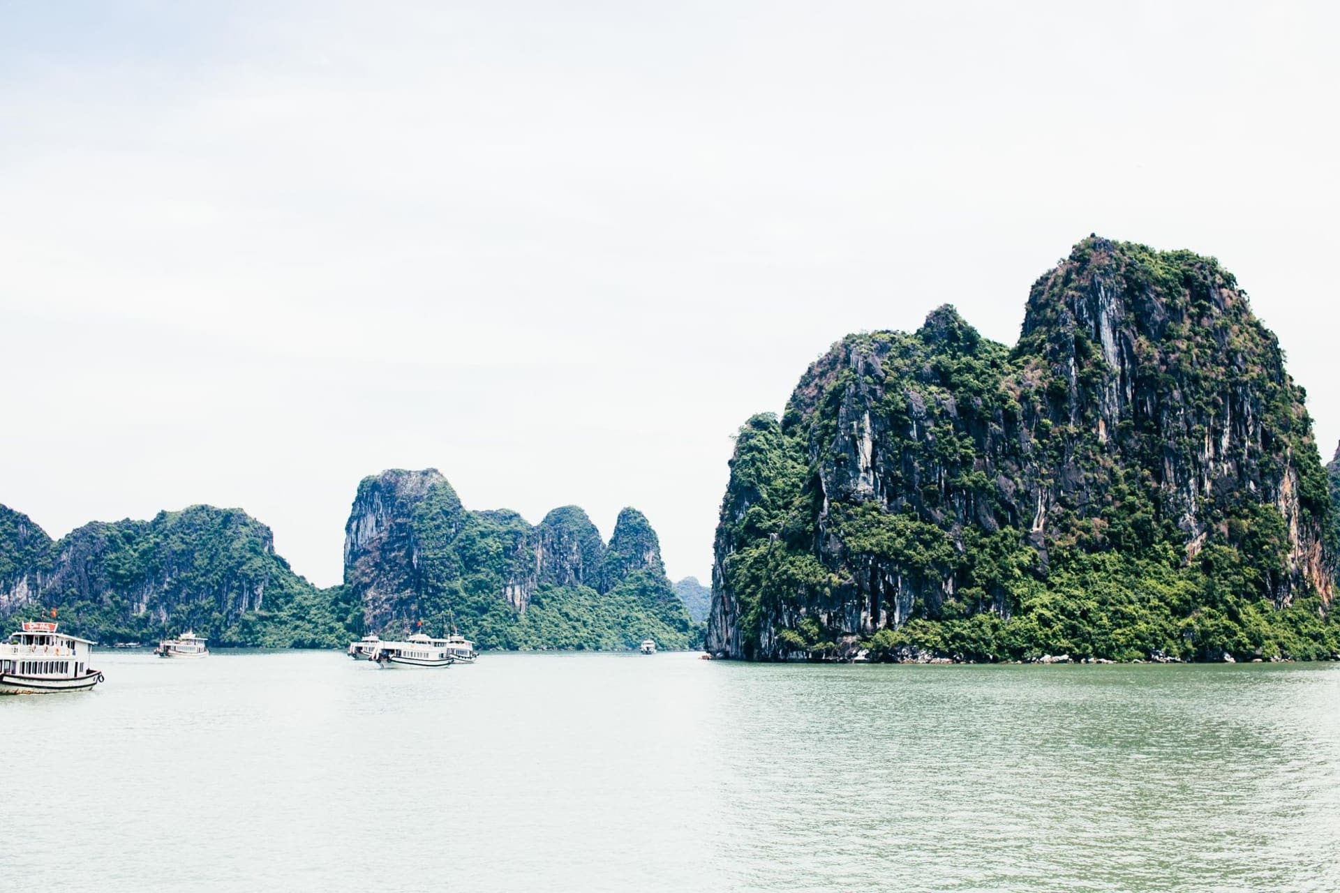 Dramatic limestone karst formations rising from calm emerald waters at Hạ Long Bay, Vietnam