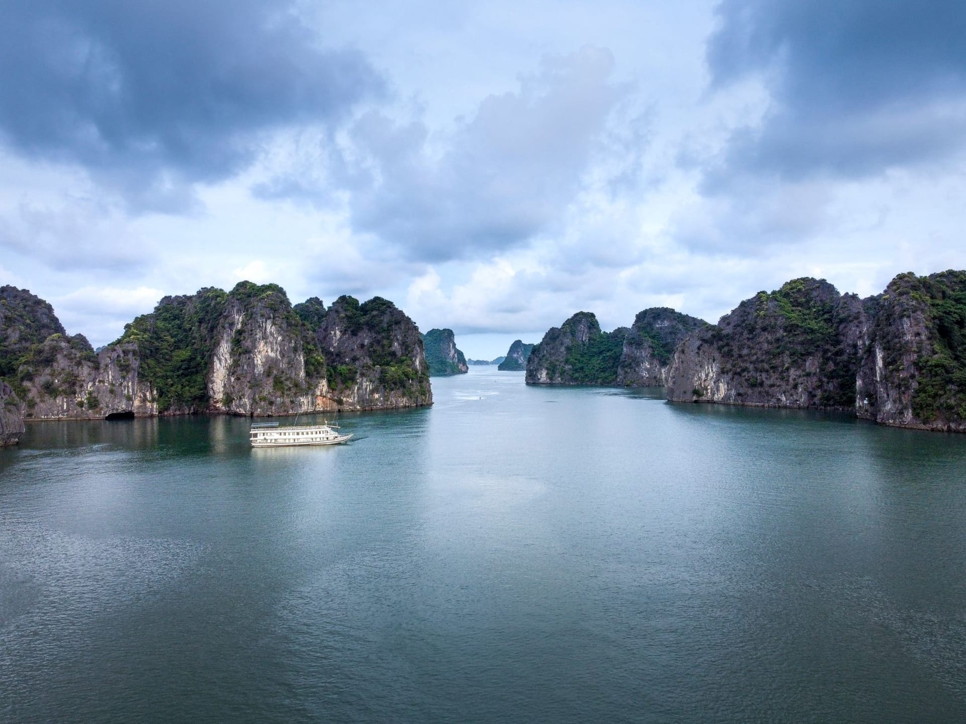 A macaque monkey sitting on a beach rock at Monkey Island with limestone karsts reflected in the turquoise sea behind it