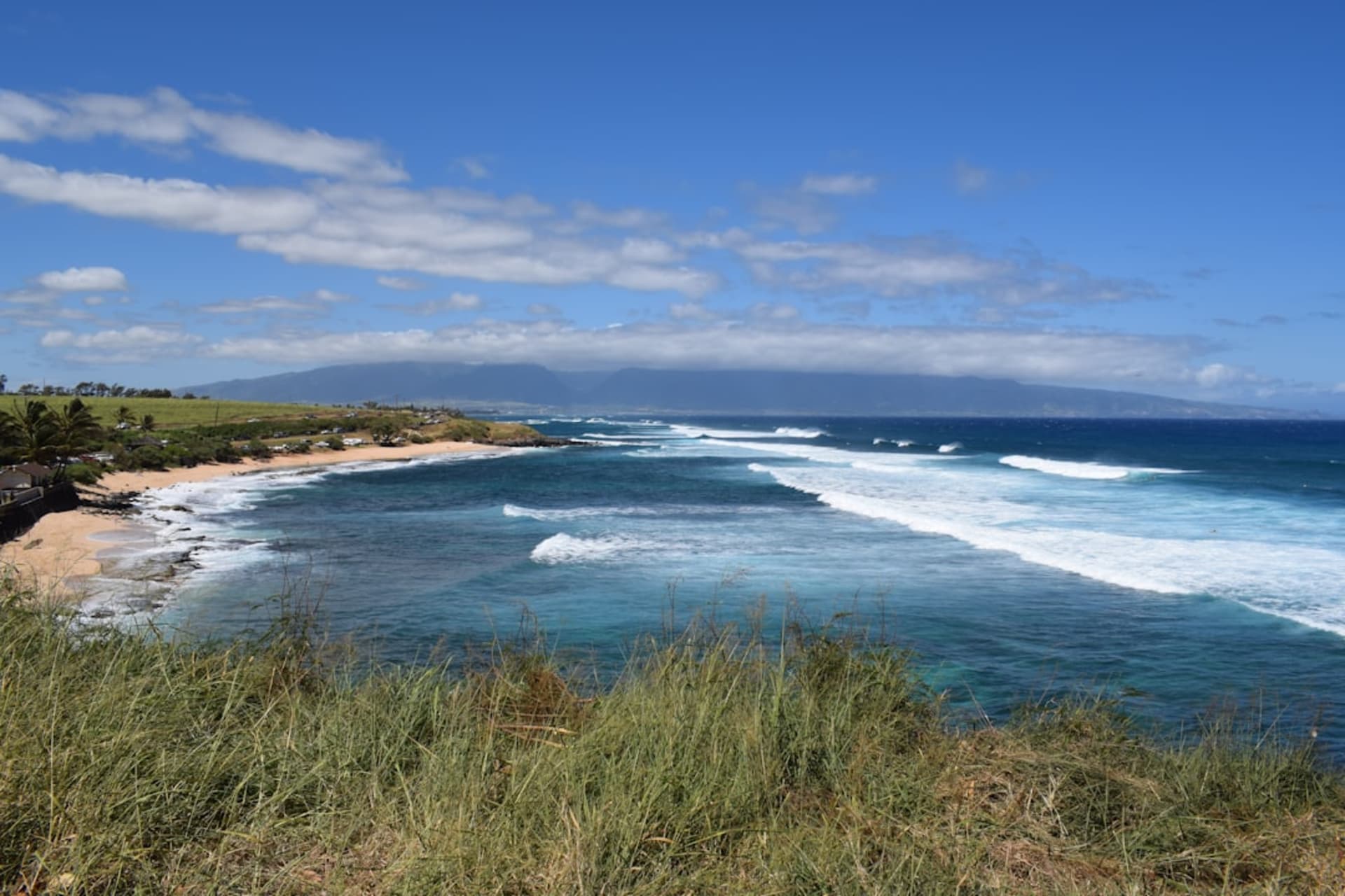 Le phare historique blanc de Kilauea Point se dressant sur un promontoire verdoyant au-dessus de l'océan, avec des oiseaux marins tournoyant au-dessus.