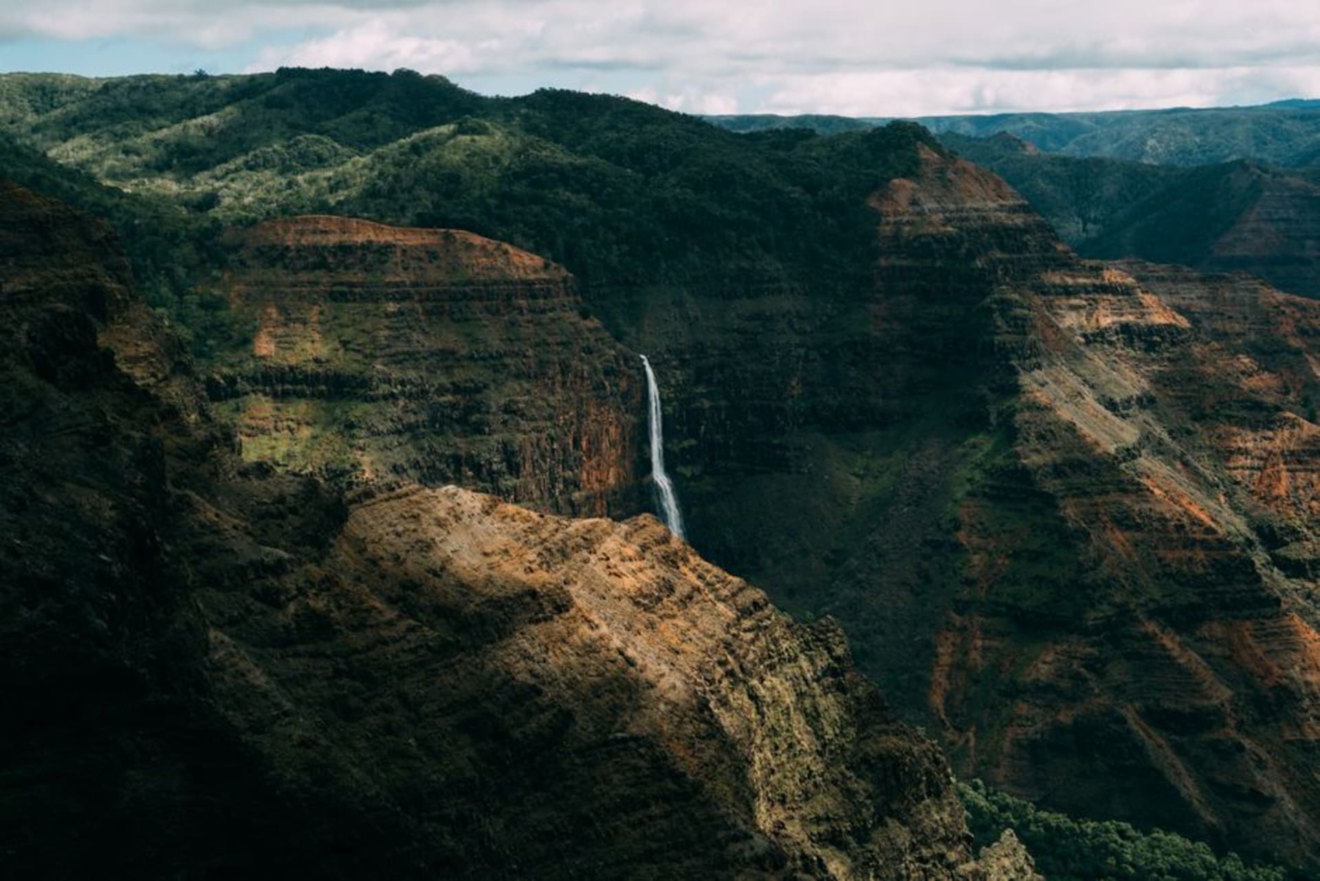 View from Kalalau Lookout in Koke'e State Park over the green ridgelines of the Kalalau Valley with clouds drifting through the folds.