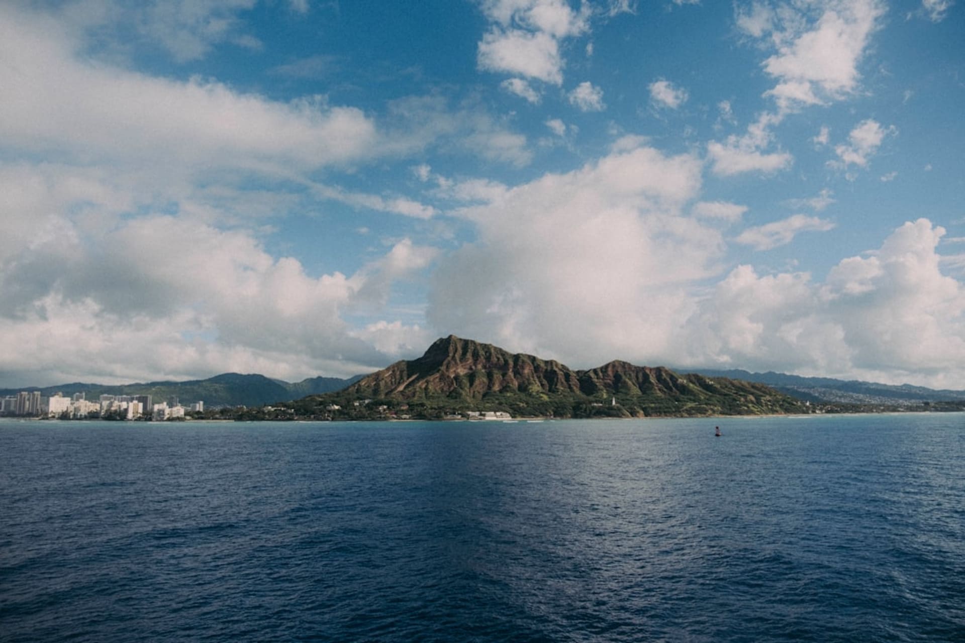 Playa de arena dorada en Makaha, en la Costa Waianae de Oahu, con grandes olas rompiendo y las montañas Waianae de fondo