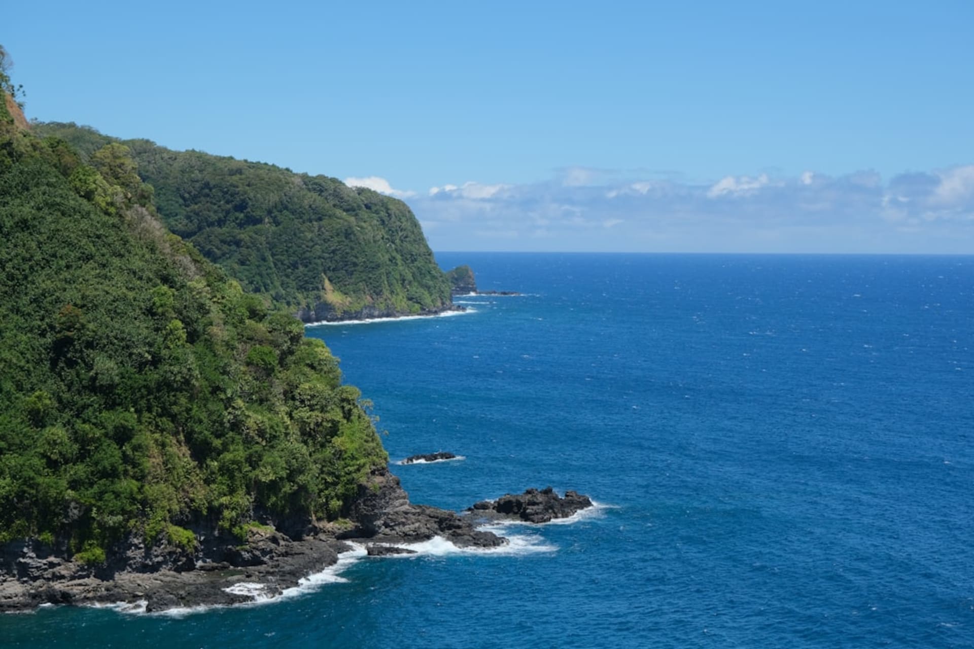 El mirador del Valle de Pololu en la Big Island de Hawai'i, mostrando una playa de arena negra al pie de acantilados marinos verdes