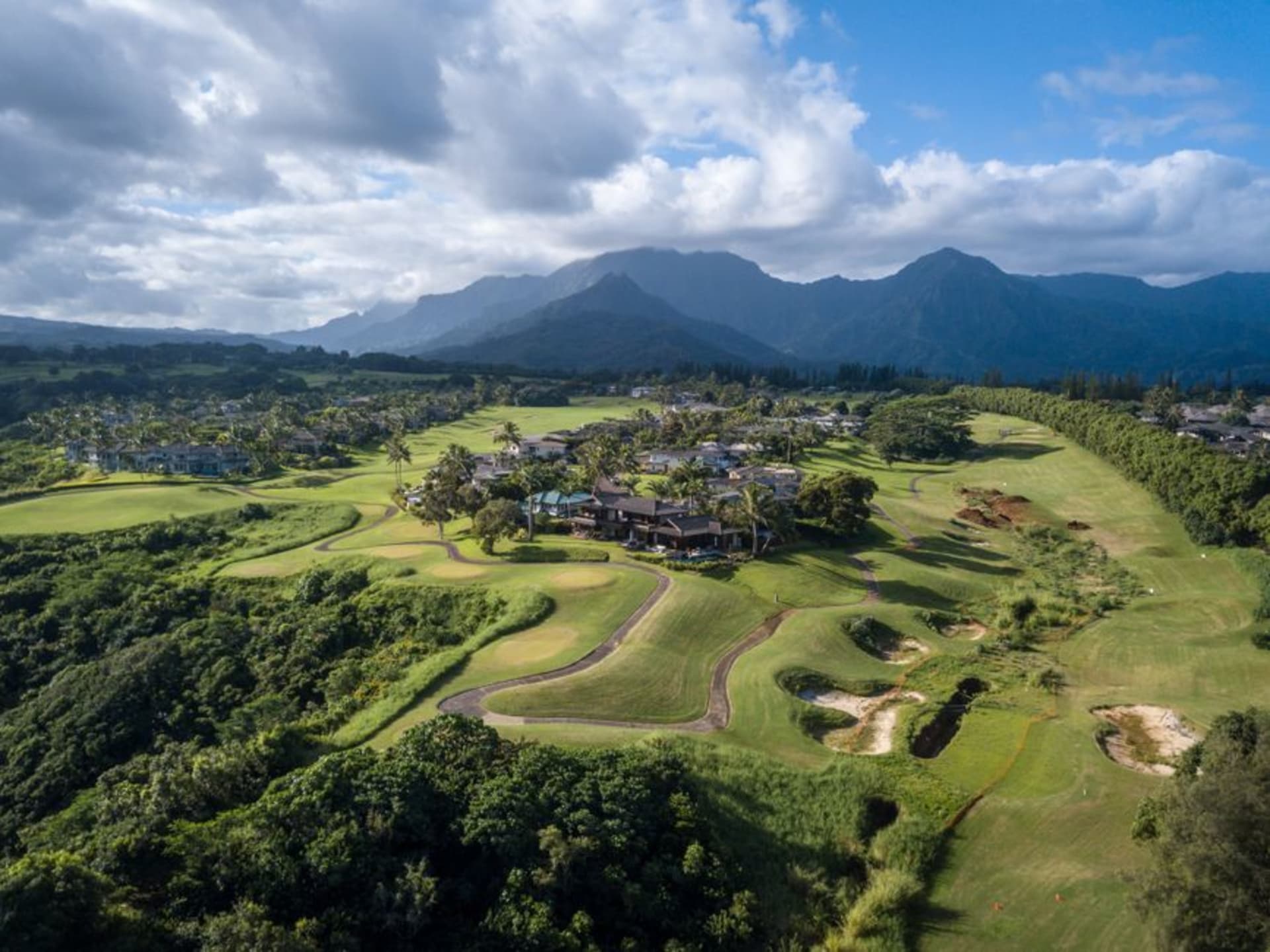 Vista desde los acantilados de Princeville sobre las aguas turquesa de la bahía de Hanalei, enmarcada por montañas verdes dramáticas.