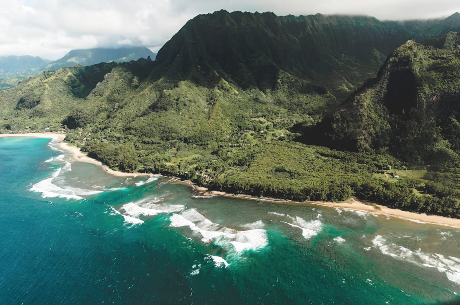 The Great Wall and reconstructed thatched structures of Pu'uhonua o Honaunau National Historical Park beside a turquoise cove