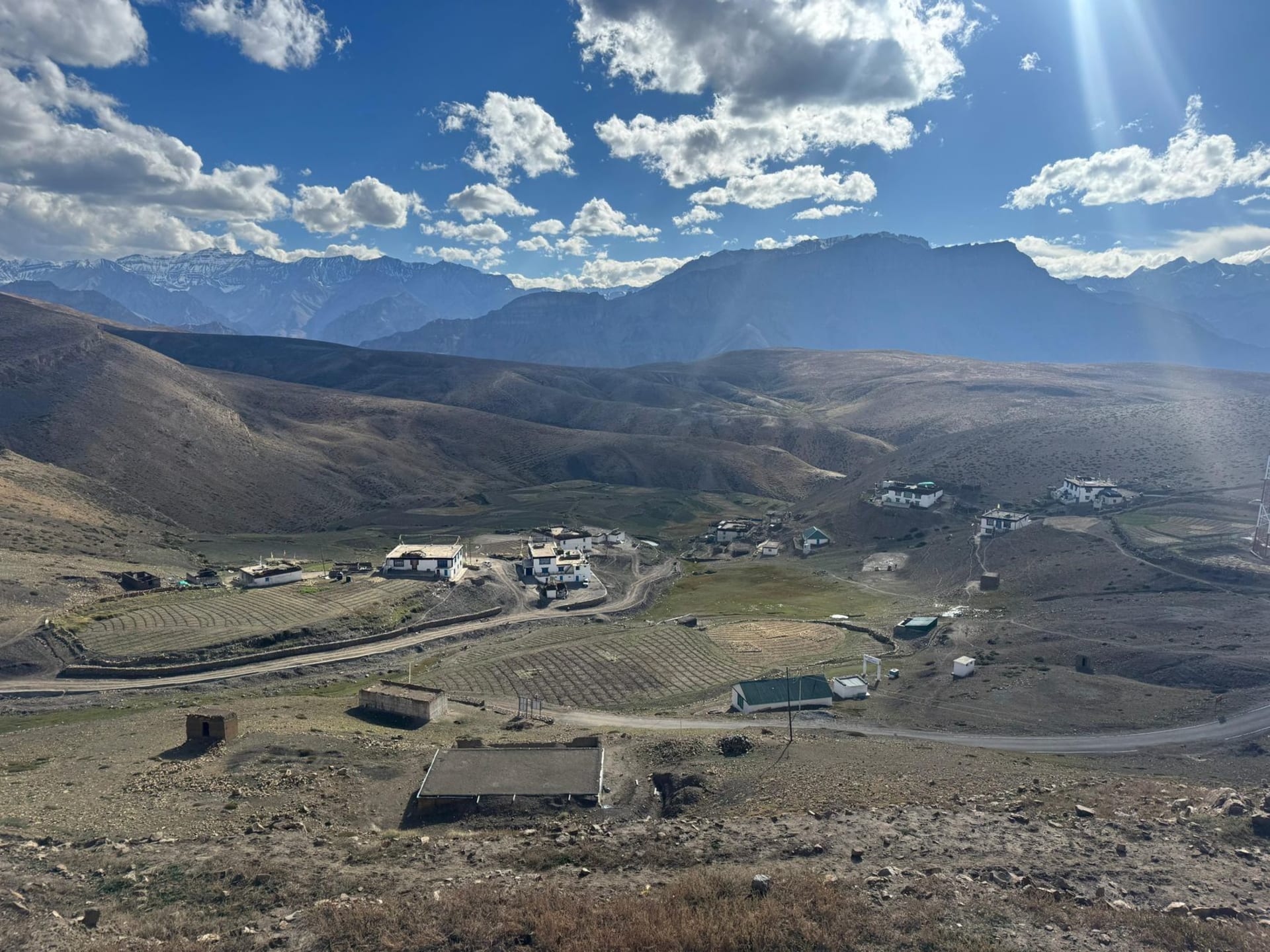 Dhankar monastery and village buildings stacked impossibly on a thin pinnacle of eroded clay rock above the vast brown confluence of the Pin and Spiti rivers far below