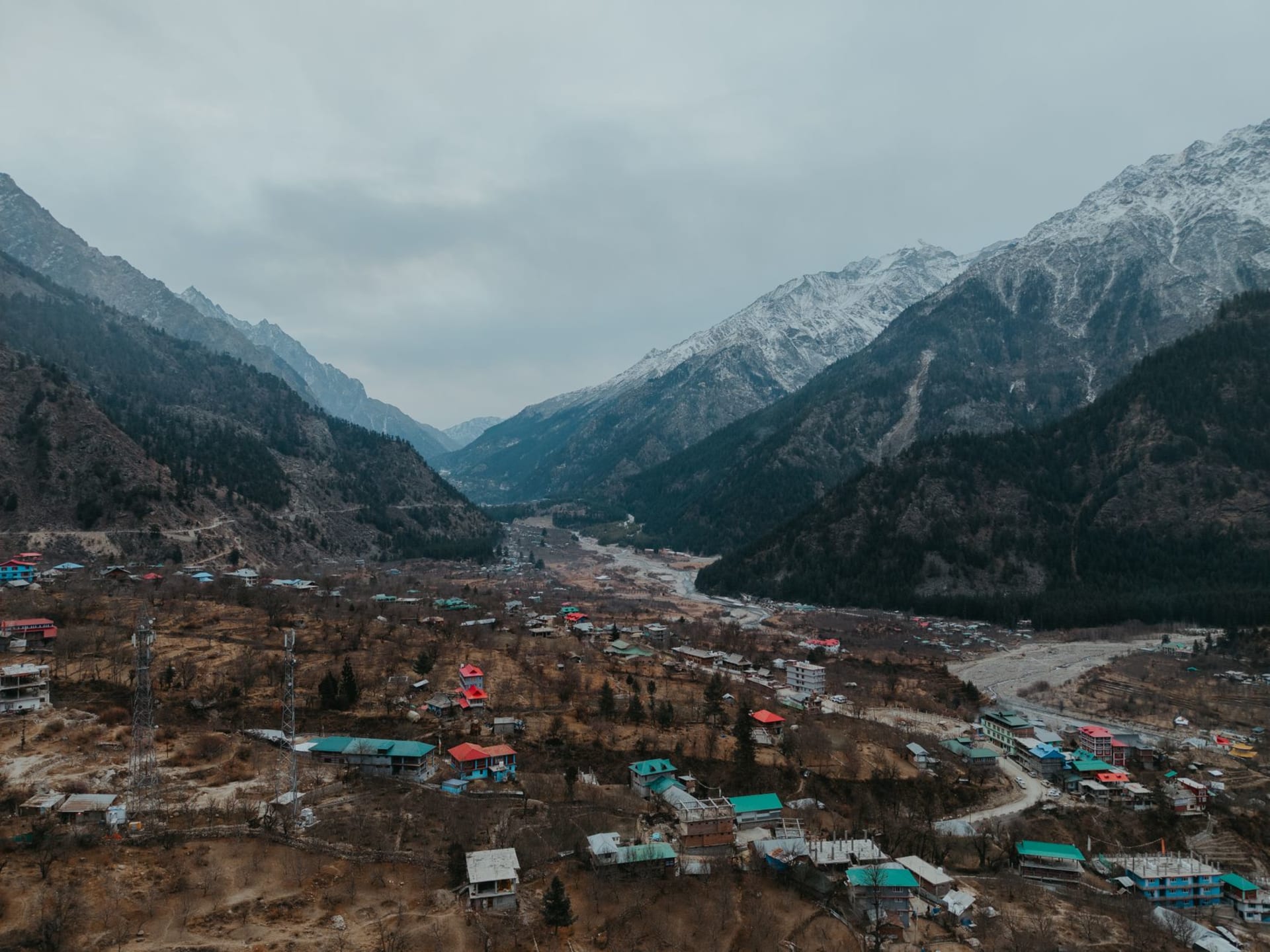 Sangla Valley's lush green river meadows and terraced fields with dense pine and deodar forest climbing steeply to bare high ridges above