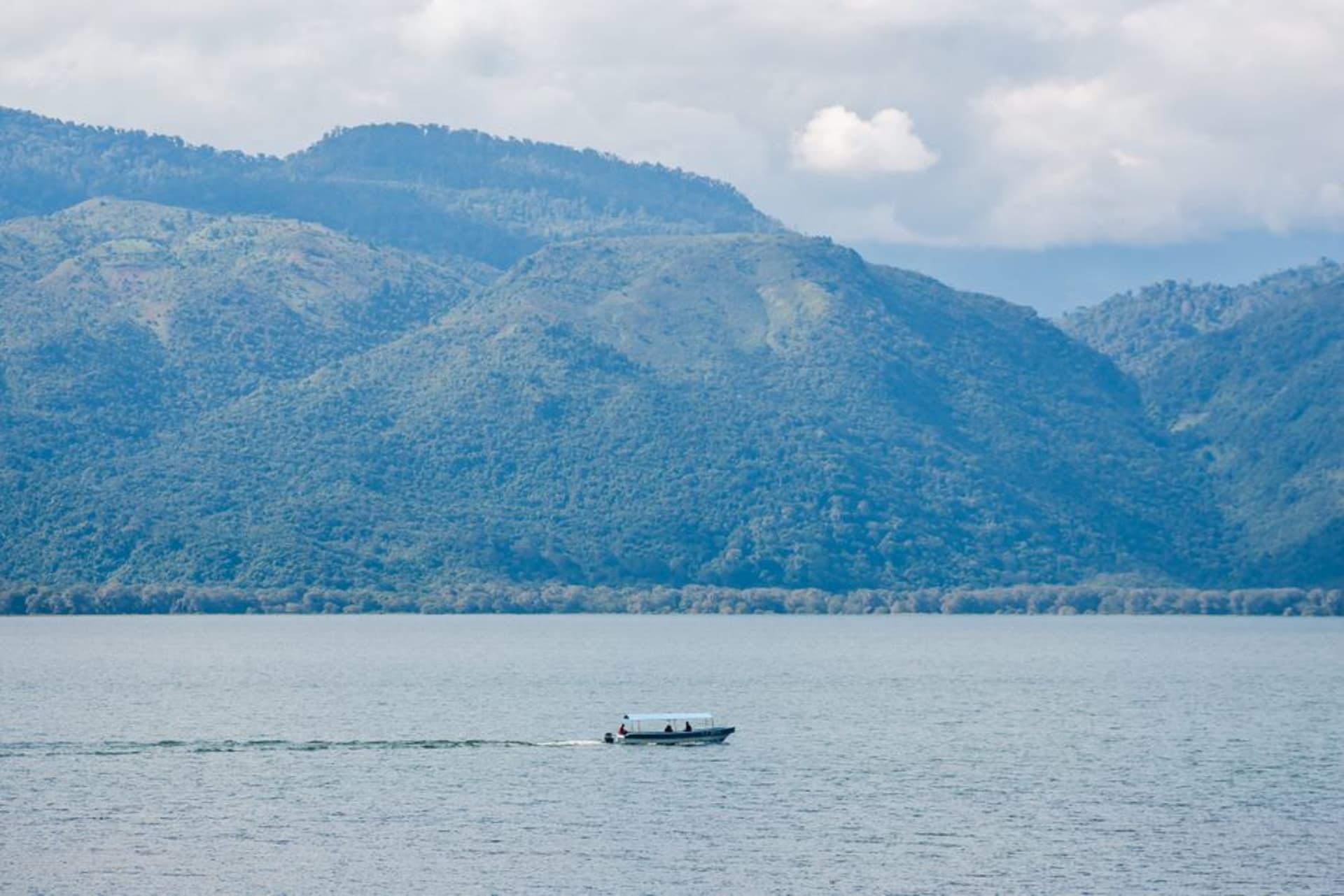 A small wooden fishing boat crossing the calm waters of the Gulf of Fonseca toward the volcanic cone of Isla del Tigre