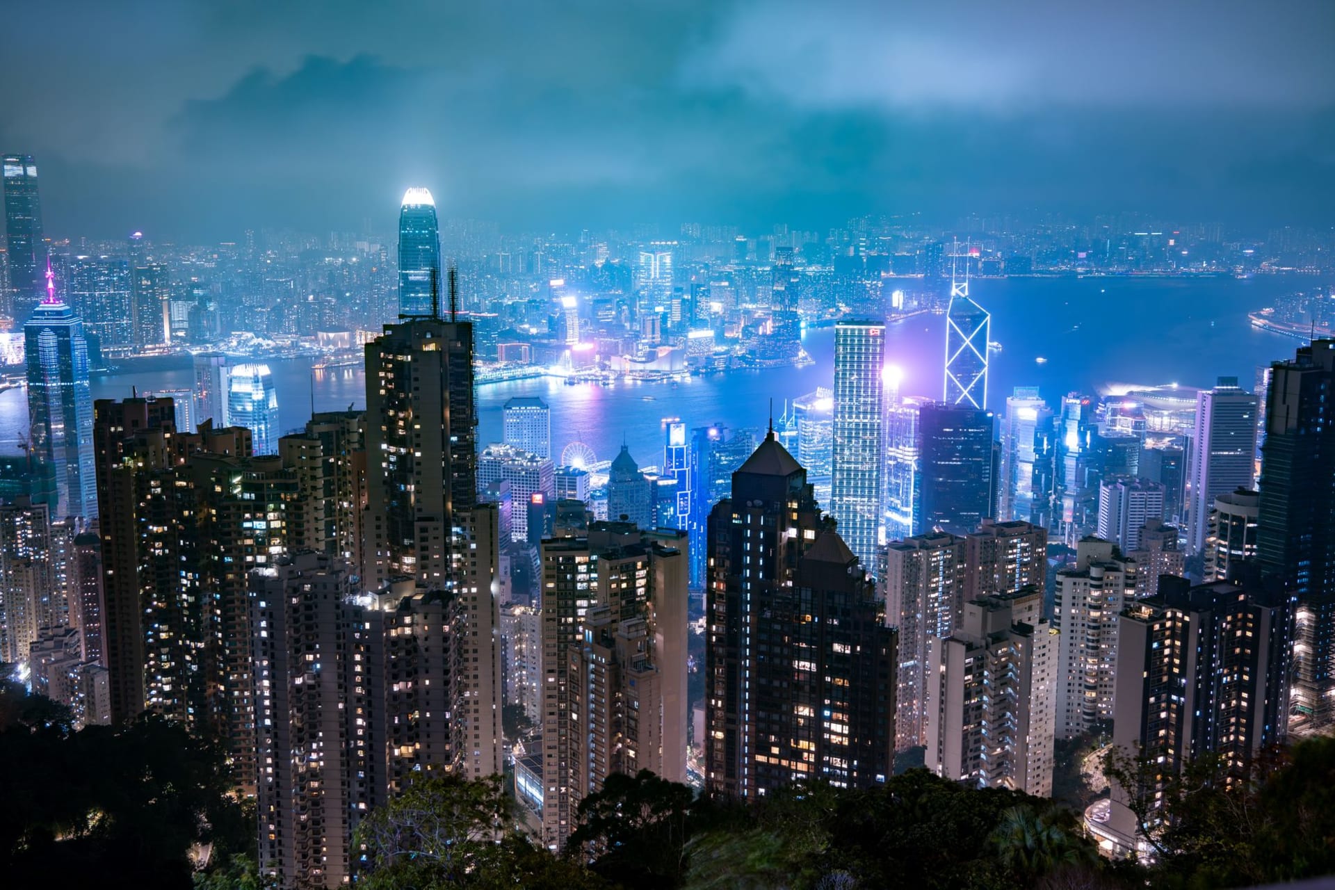 Hong Kong skyline at night with illuminated skyscrapers reflected across Victoria Harbour