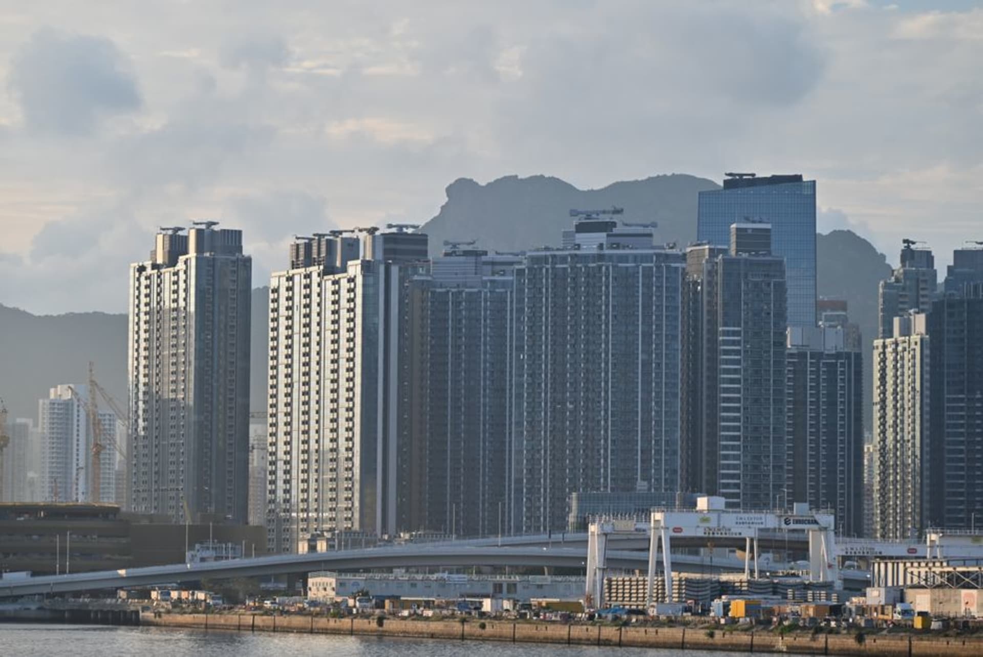 Mesas de dai pai dong frente al puerto en Kennedy Town al atardecer, con la baranda del paseo marítimo en primer plano
