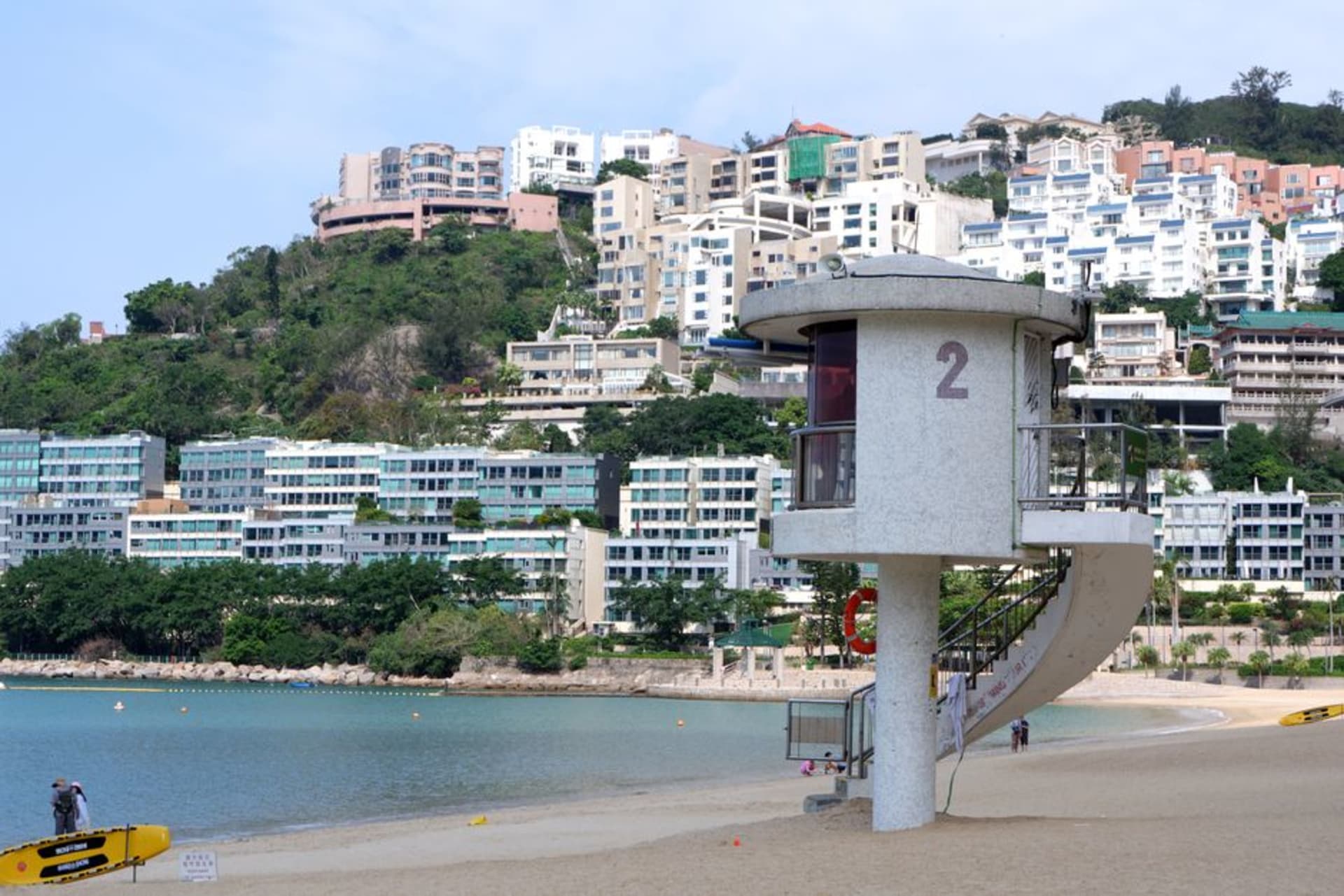 La playa de Repulse Bay con agua turquesa y torres residenciales alzándose detrás de la arena