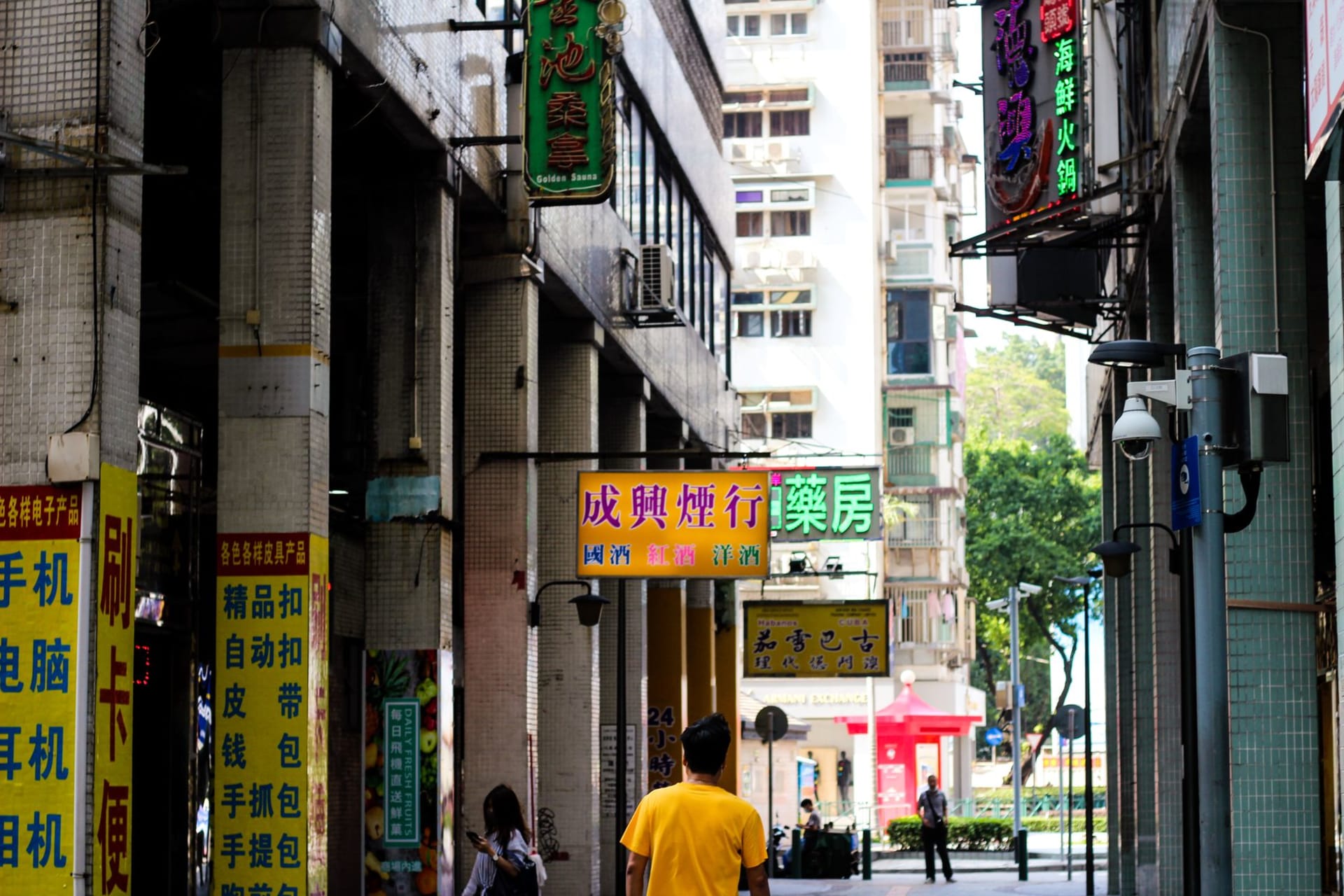 Stalls of electronic components and gadget parts lining a Sham Shui Po pavement under fluorescent light at night