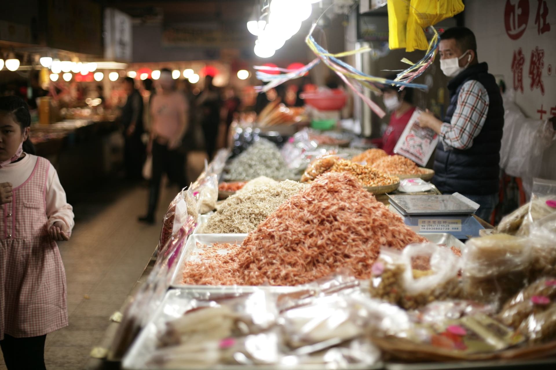 Dried seafood hanging in bundles outside shop fronts on a narrow Sheung Wan street in morning light