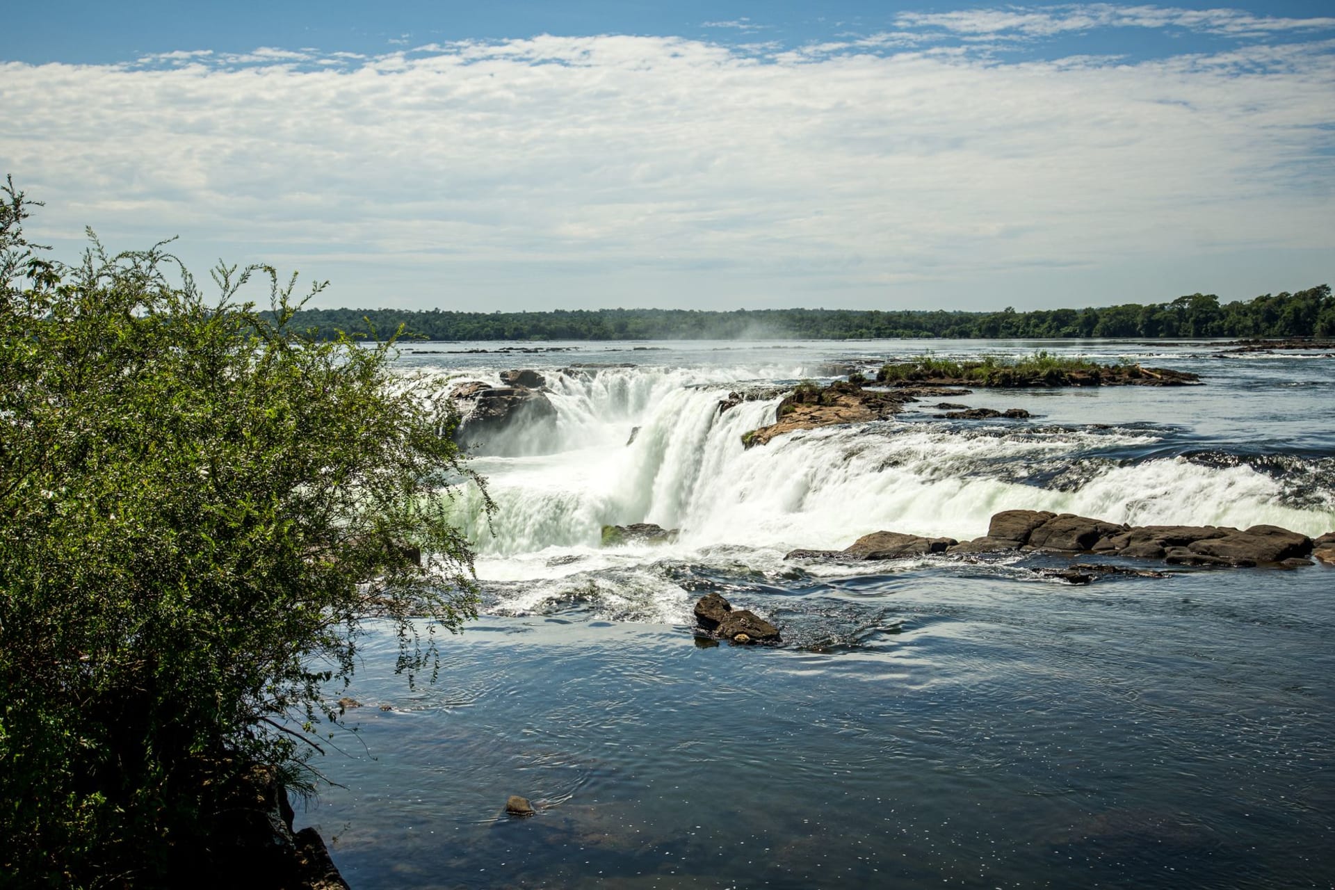 Sunset over Puerto Iguazú waterfront where the Iguazú and Paraná rivers meet, with a small dock and local boats in the foreground