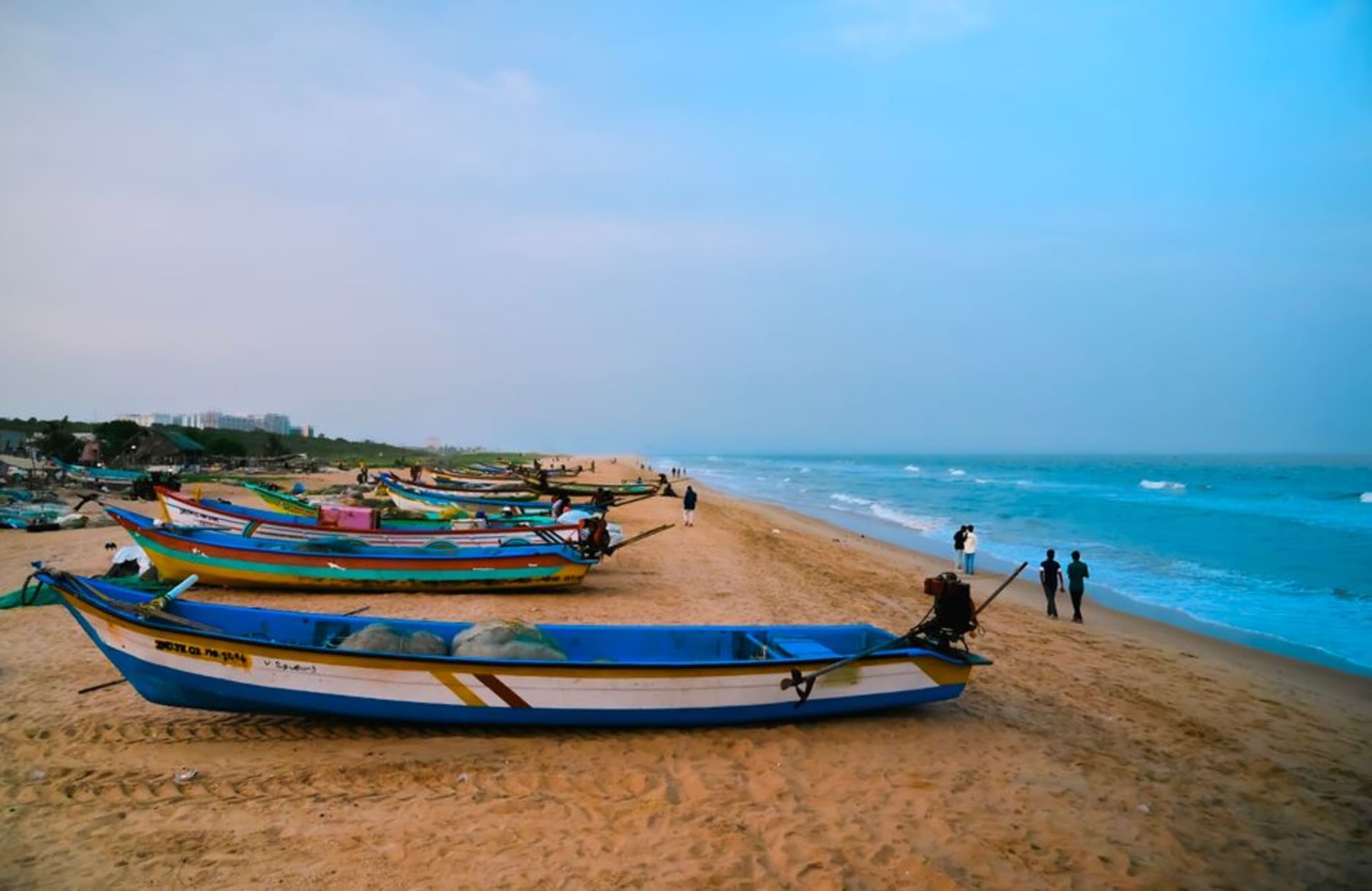 Marina Beach at sunrise with fishing boats pulled up on the sand and the city skyline behind