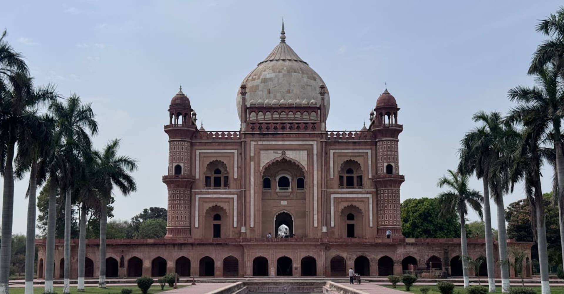 The red sandstone arches of the Jama Masjid mosque with Delhi skyline behind