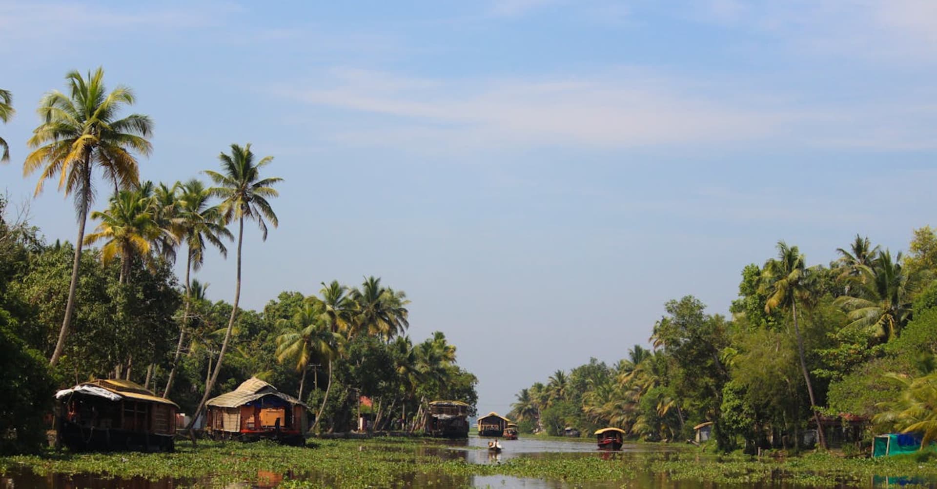 Traditional houseboat gliding through palm-lined backwaters in Kerala