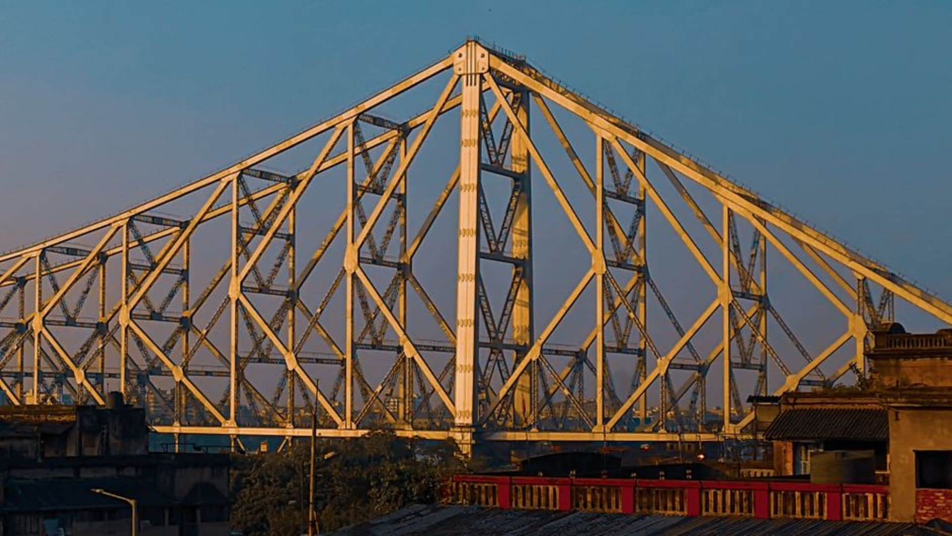 Howrah Bridge spanning the Hooghly River at dusk with city lights beginning to glow