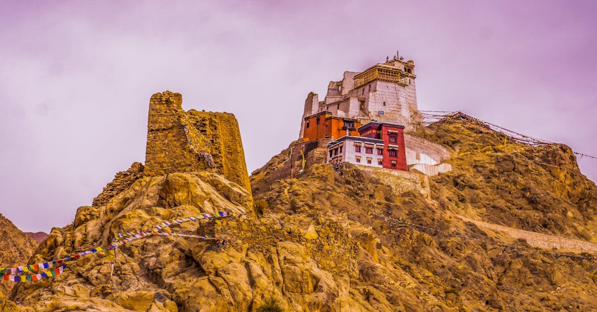 Buddhist monastery perched on a cliff above barren mountains in Ladakh
