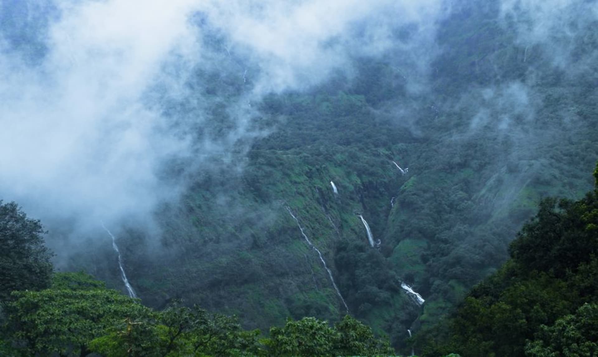 A waterfall cascading down green monsoon hillsides in the Sahyadri range near Lonavala