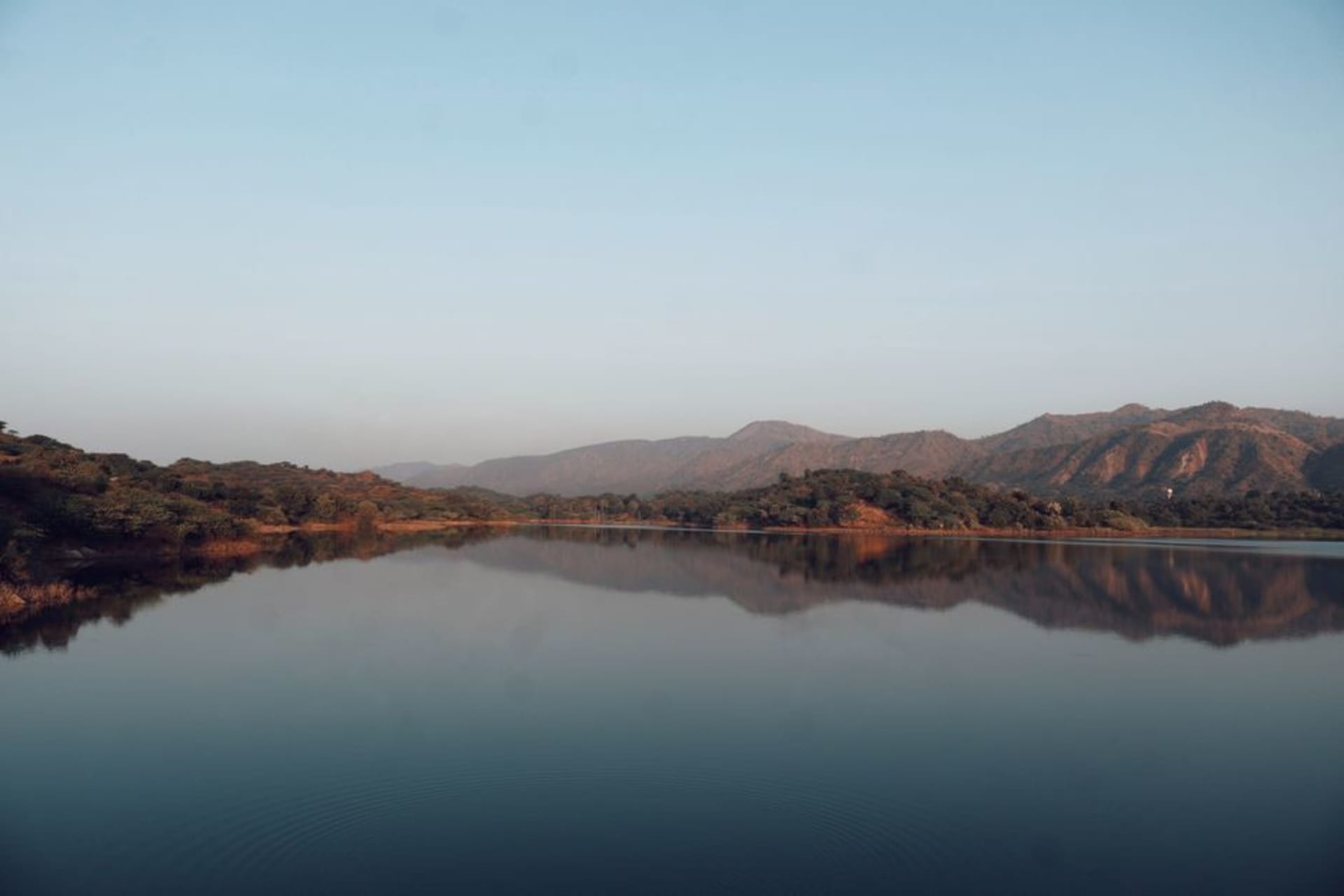 Mist rising over Nakki Lake with forested hills of Mount Abu behind