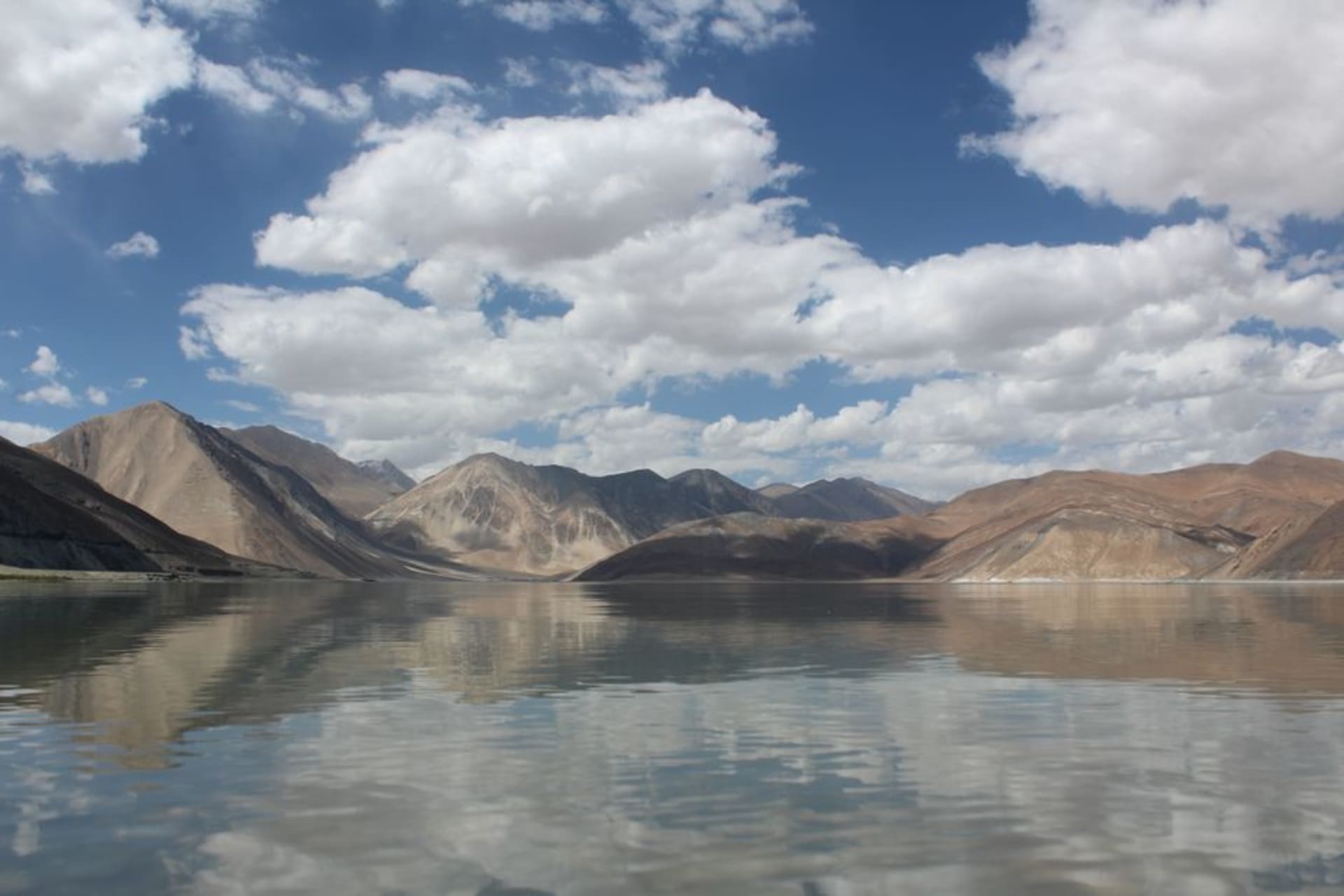 Pangong Lake's turquoise water stretching toward barren mountains under a clear sky