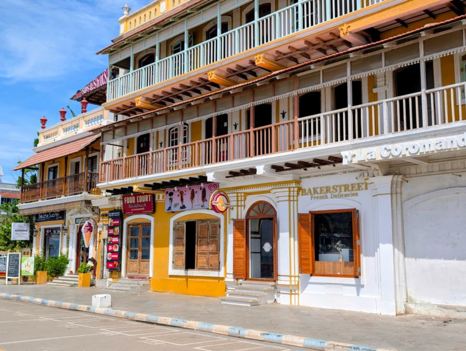 A mustard-yellow colonial villa with white trim and bougainvillea on a quiet street in Pondicherry's French Quarter