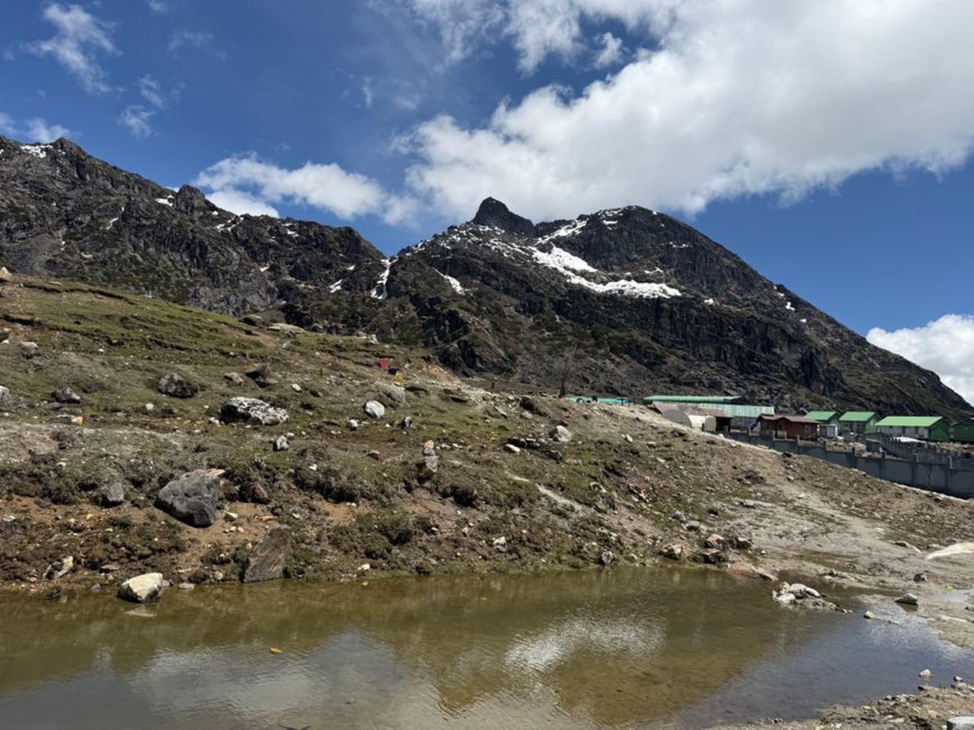 The whitewashed Tawang Monastery perched on a ridge with snow-capped Himalayan peaks behind it