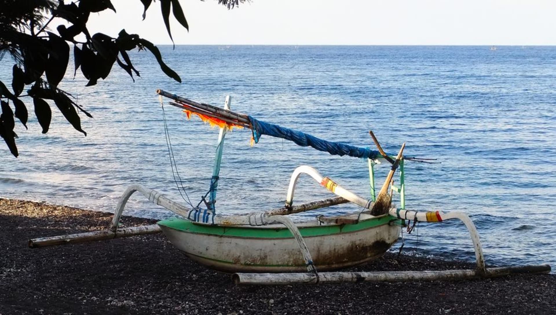 Traditional Balinese jukung outrigger boats lined up on the black sand beach at Amed