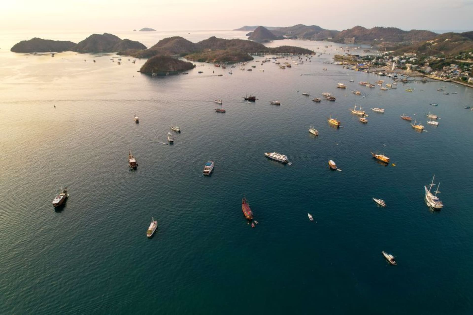 Wooden phinisi schooners anchored in Labuan Bajo harbor at sunset